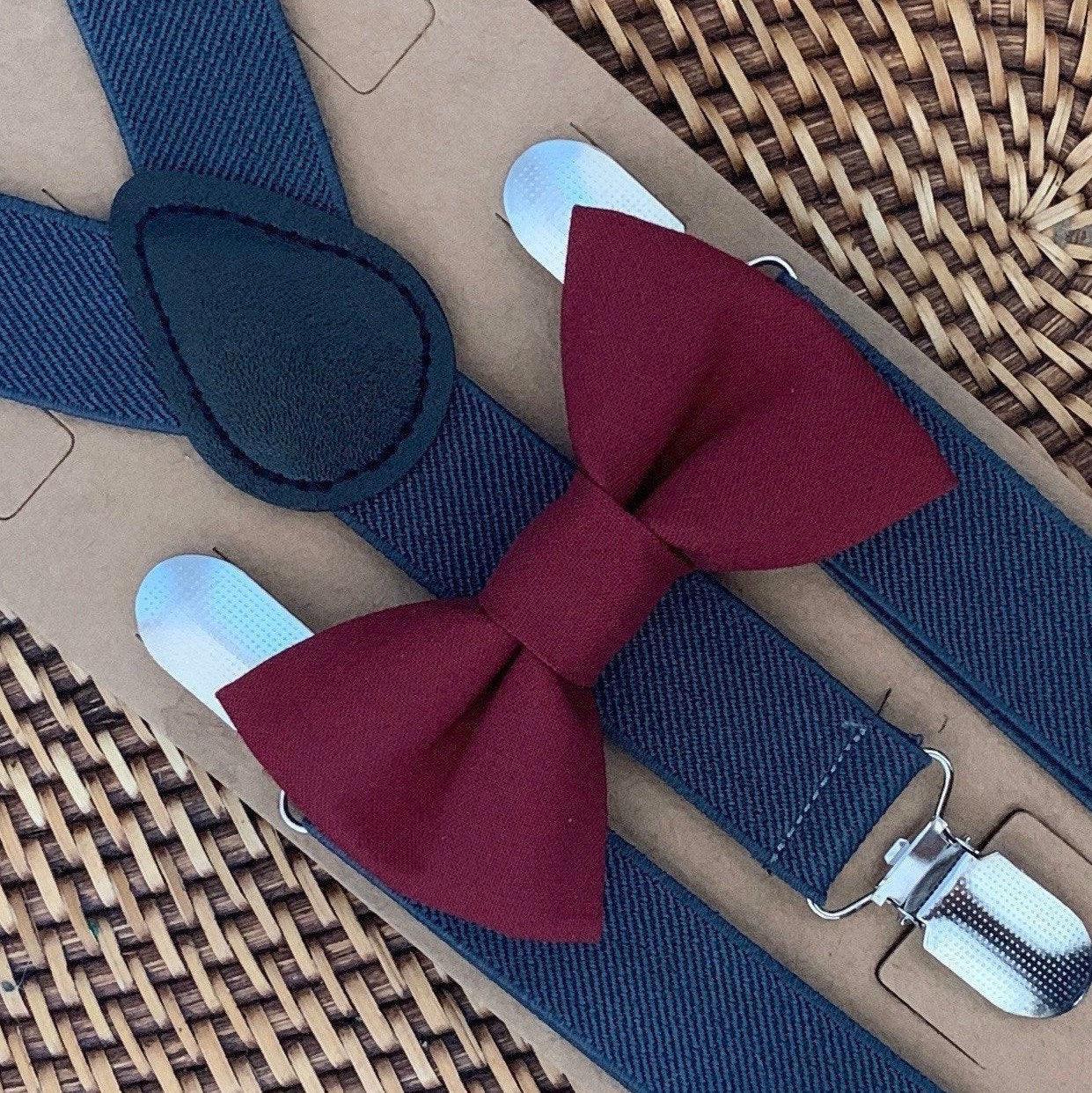 Maroon bow tie and gray suspenders on a woven surface