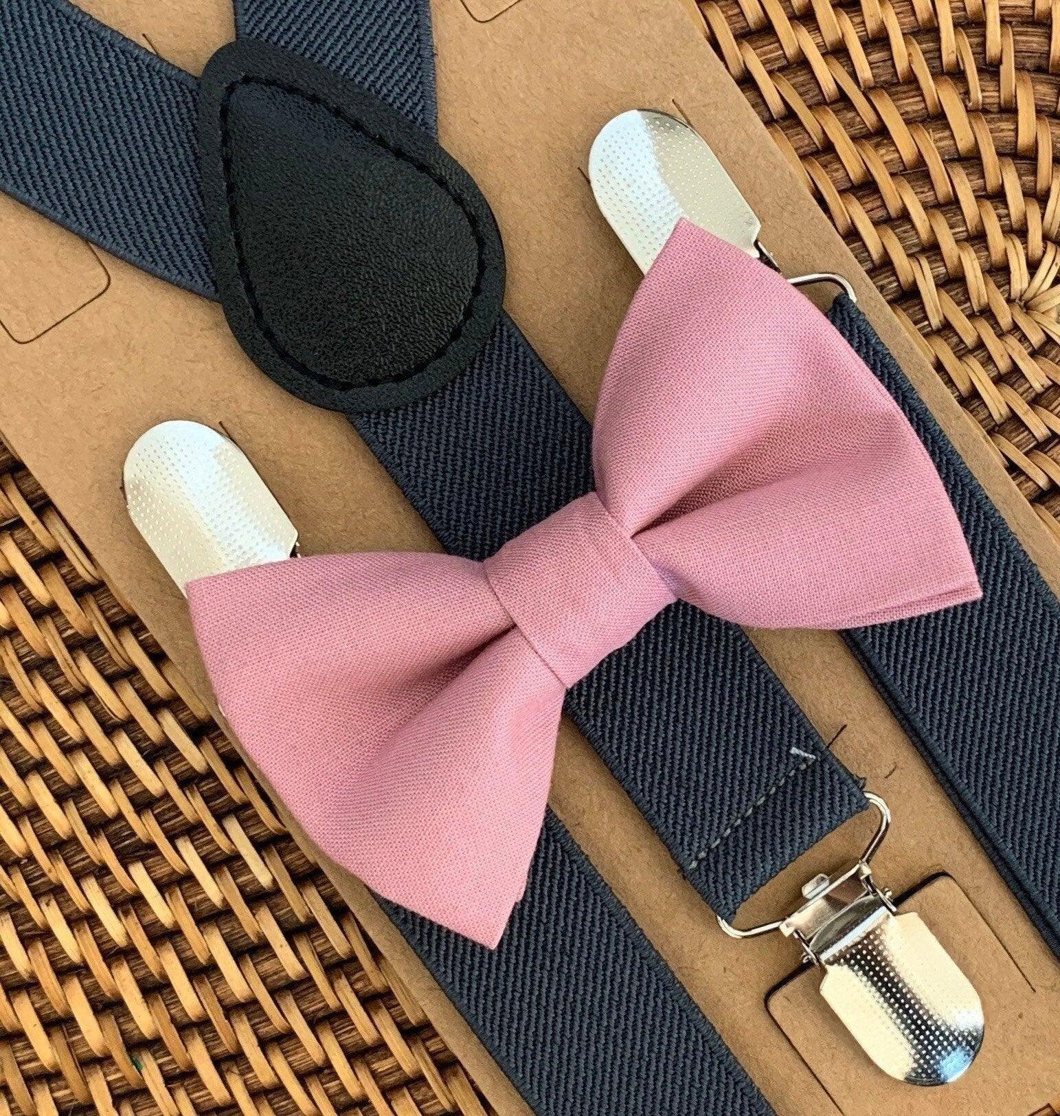 Pink bow tie with gray suspenders on a woven surface