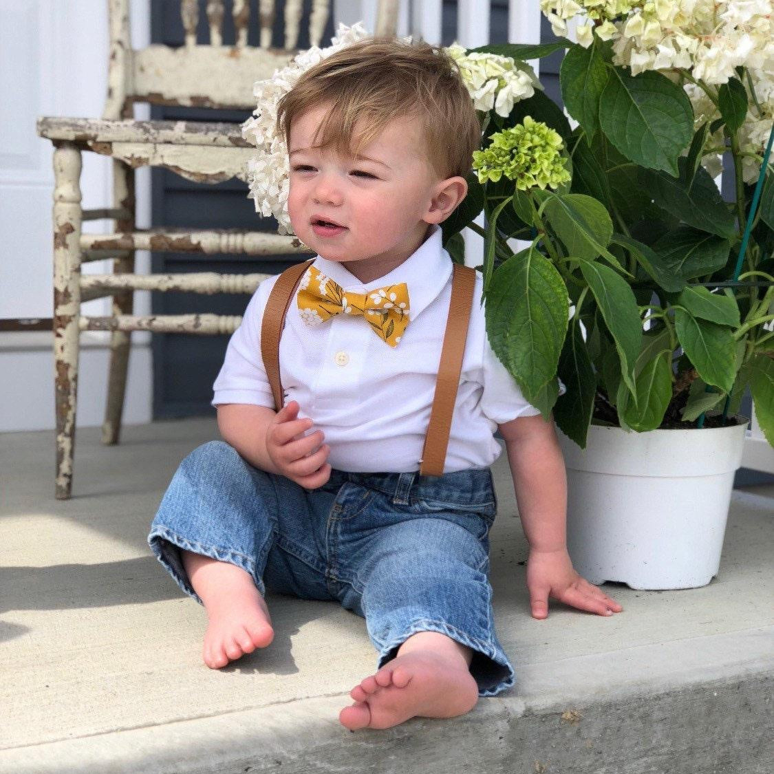 Toddler in yellow floral bow tie and brown suspenders.