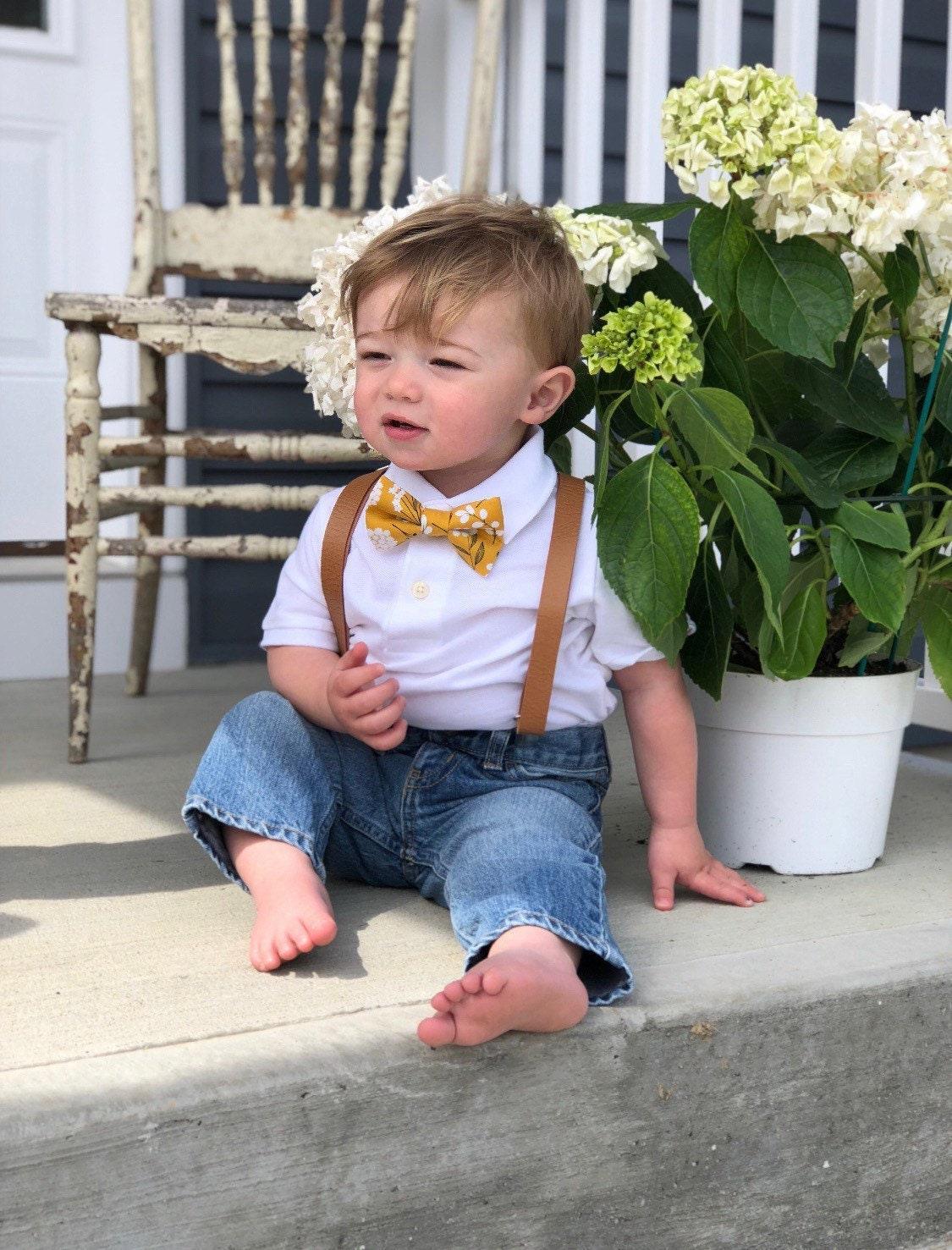 Toddler in yellow floral bow tie and brown suspenders.