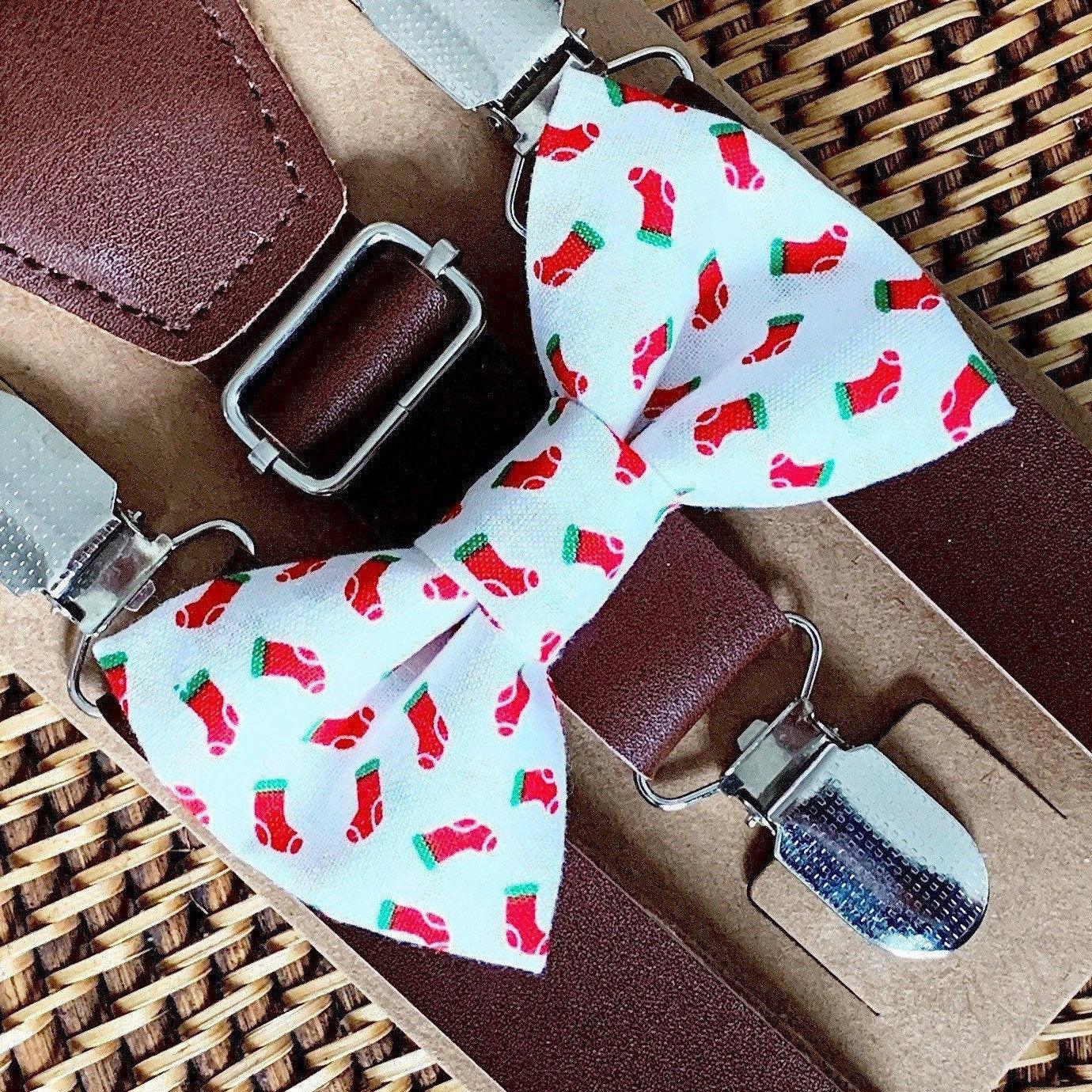 White Christmas stocking bow tie with red stocking pattern paired with dark brown vegan leather suspenders on packaging