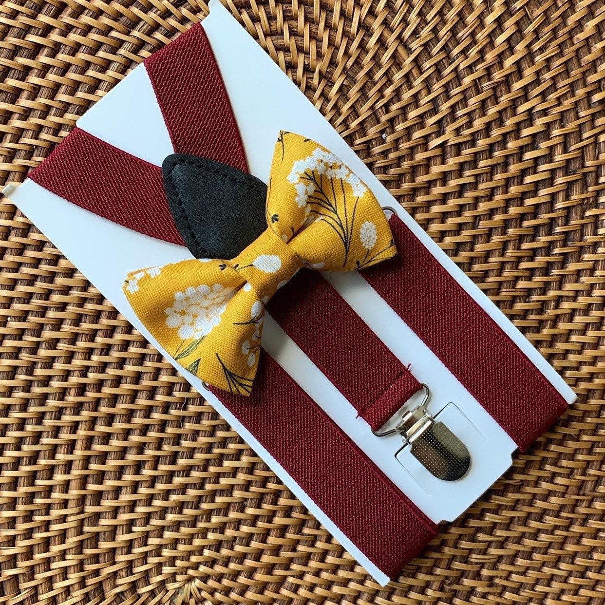 Yellow bow tie with floral pattern and burgundy suspenders on a woven surface