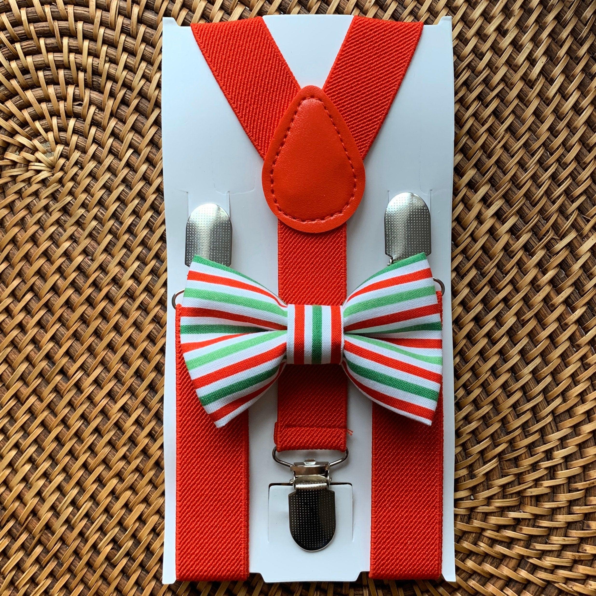 Close up of red suspenders and a striped green white red bow tie on a white packaging card