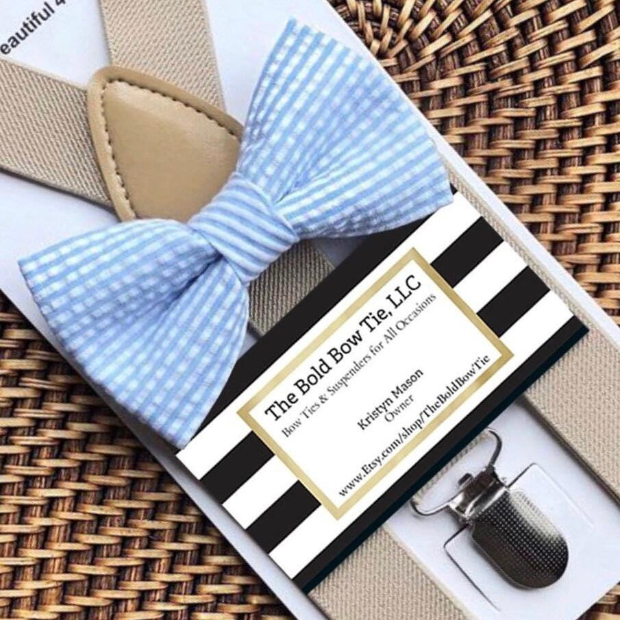 Blue striped bow tie with packaging and accessories on a woven surface