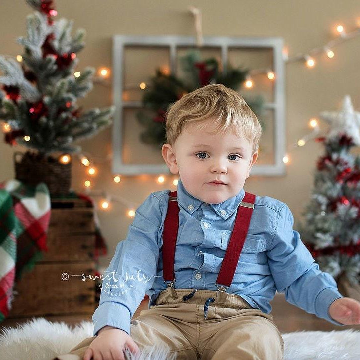 Toddler in burgundy suspenders for Christmas pictures.