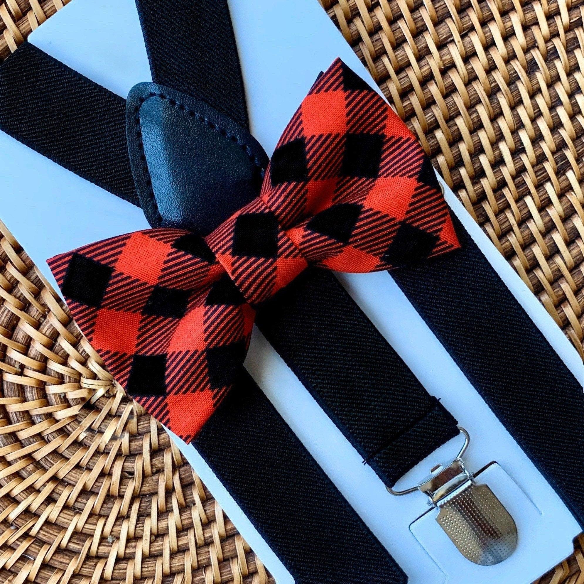 Close up of buffalo plaid red bow tie with black suspenders on a pale blue display card