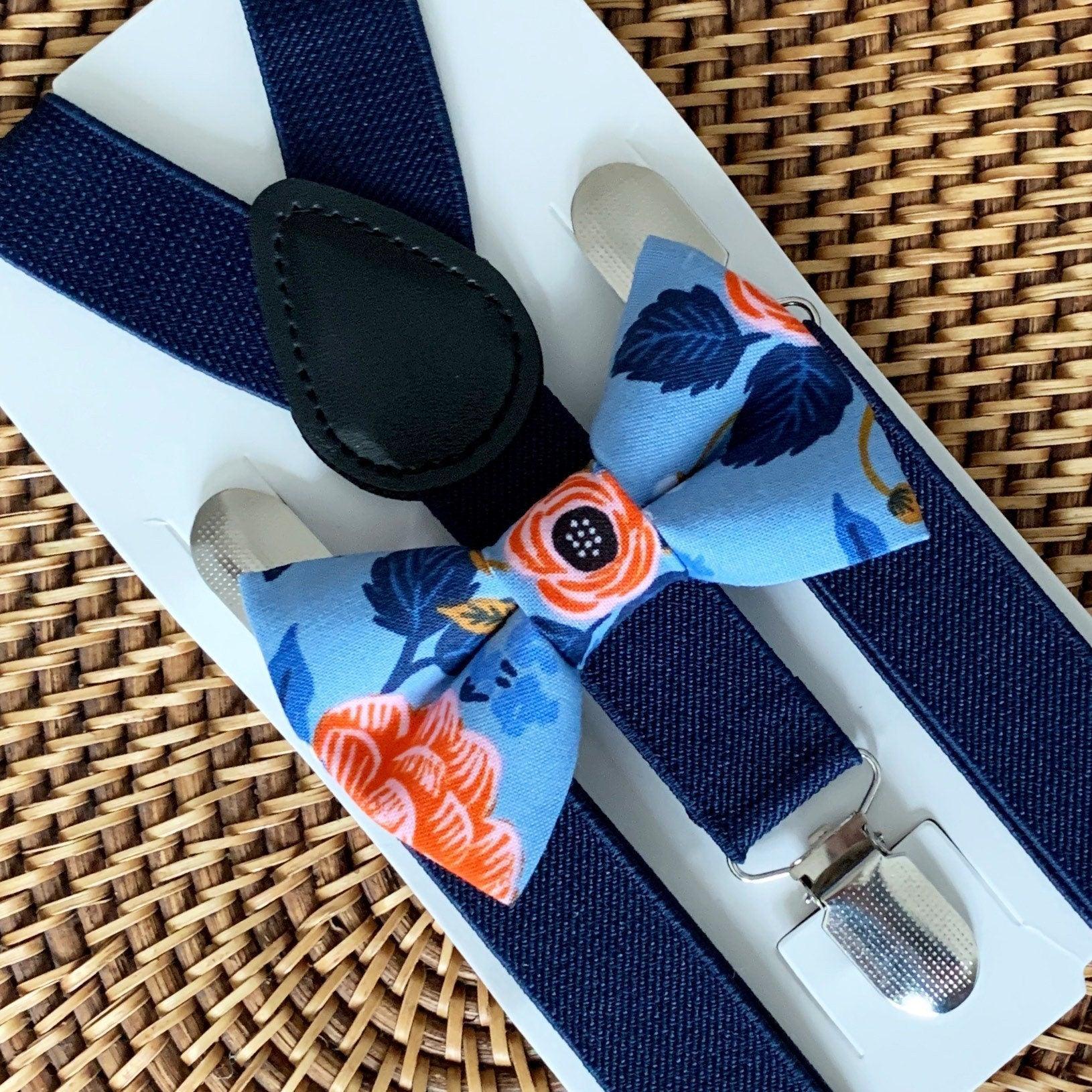 Blue floral bow tie with coral accents paired with navy suspenders on a white display card.