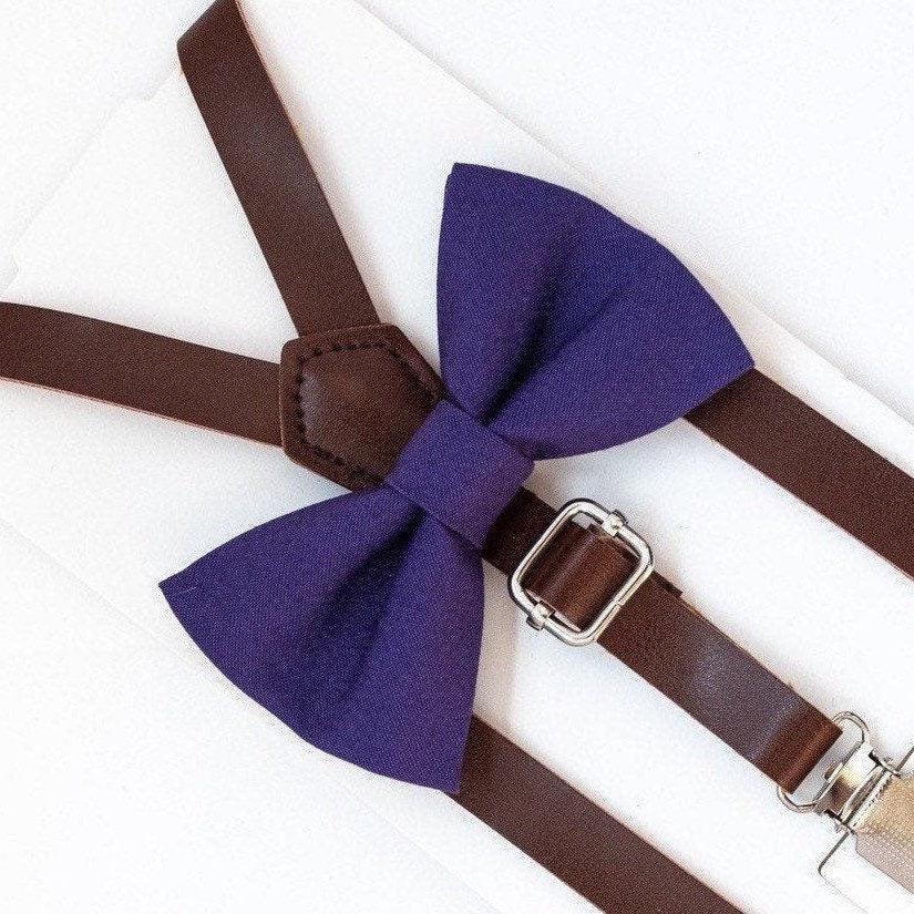 Plum bow tie with dark brown vegan leather suspenders arranged on a white background