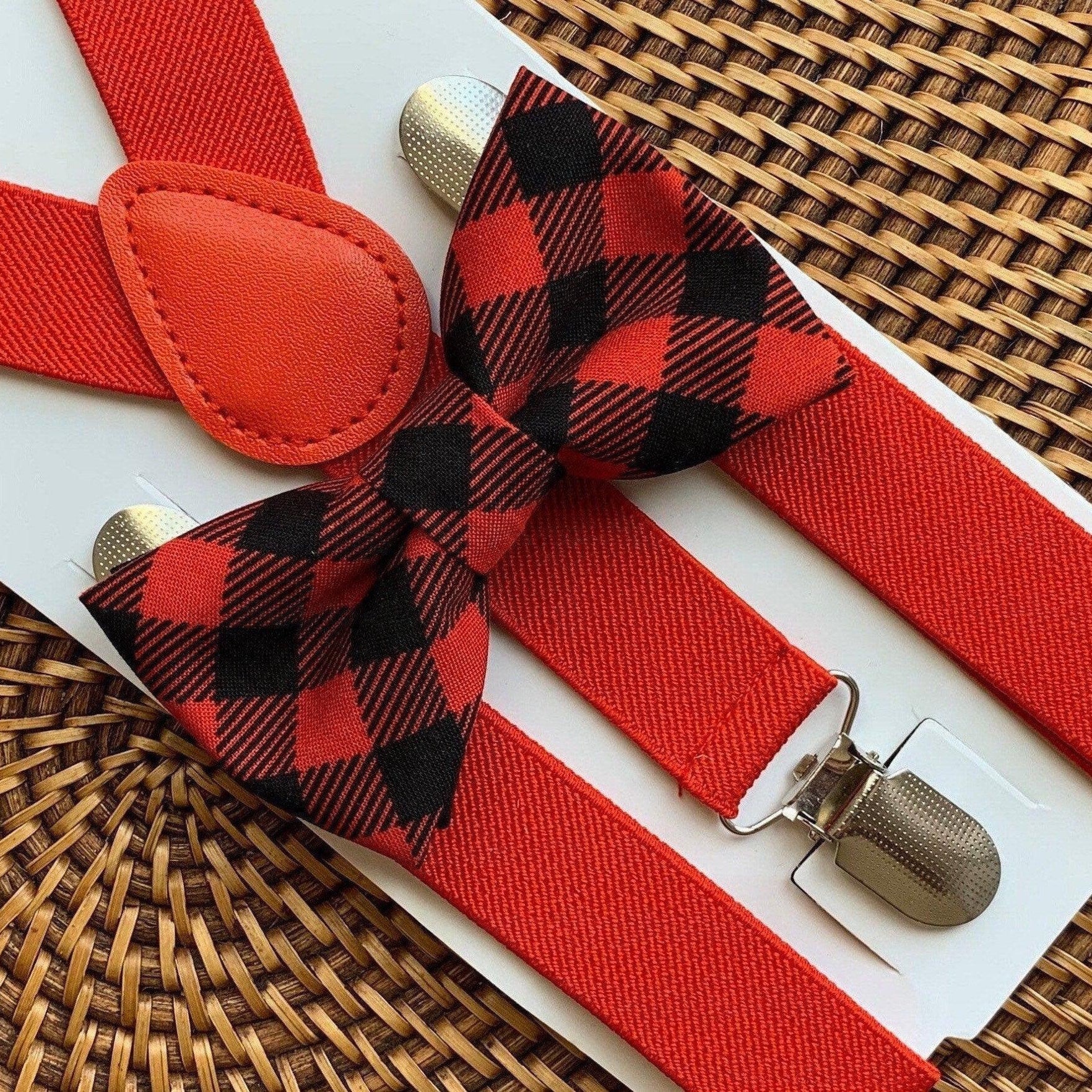 Close-up of red buffalo plaid bow tie with matching red suspenders laid on a white card over a woven surface.