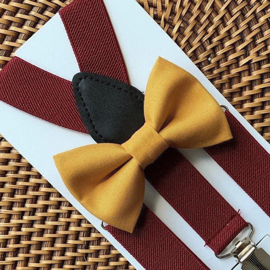 Yellow bow tie and burgundy suspenders with black buttons on a woven surface