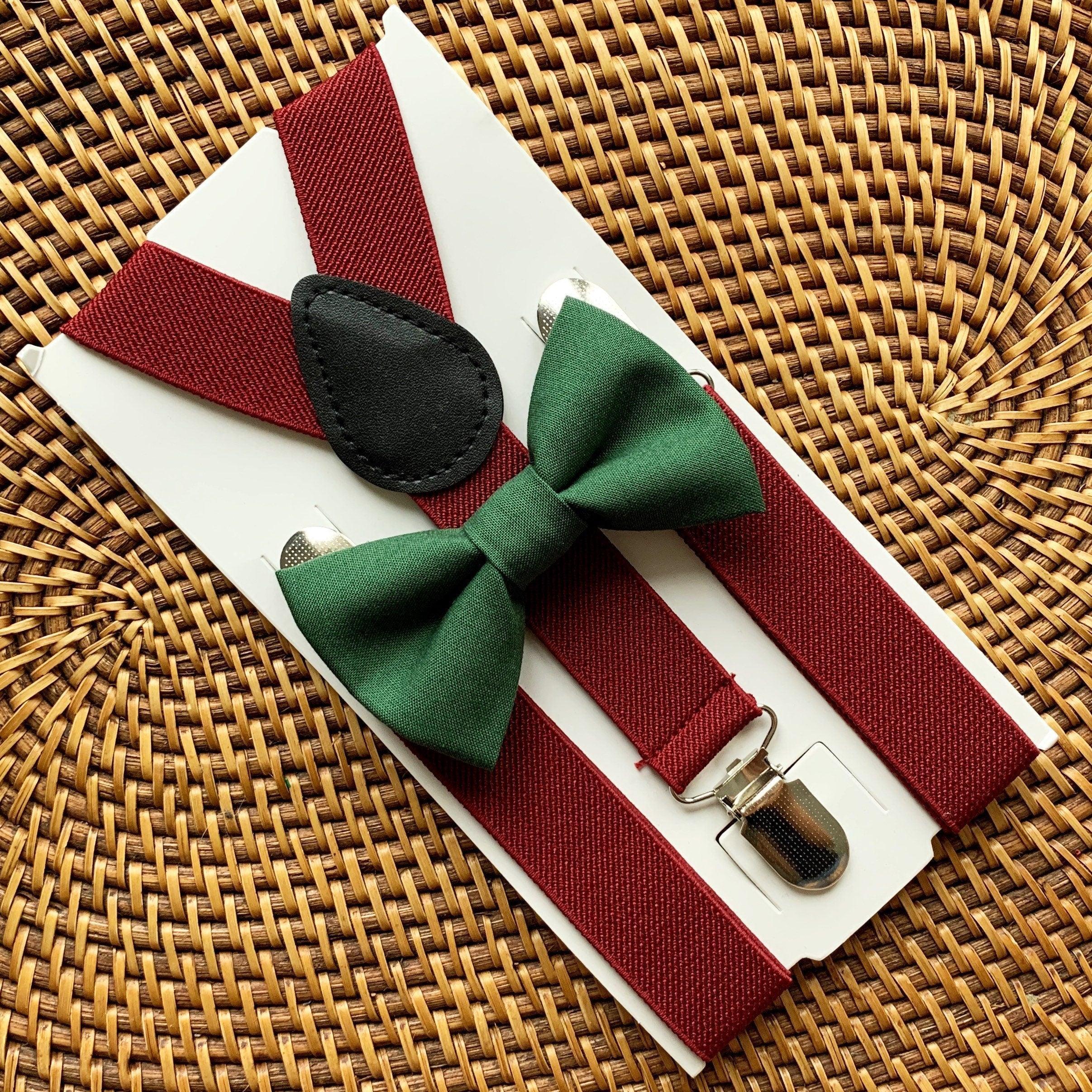 Olive green bow tie and burgundy suspenders displayed on a white card against a woven wicker background