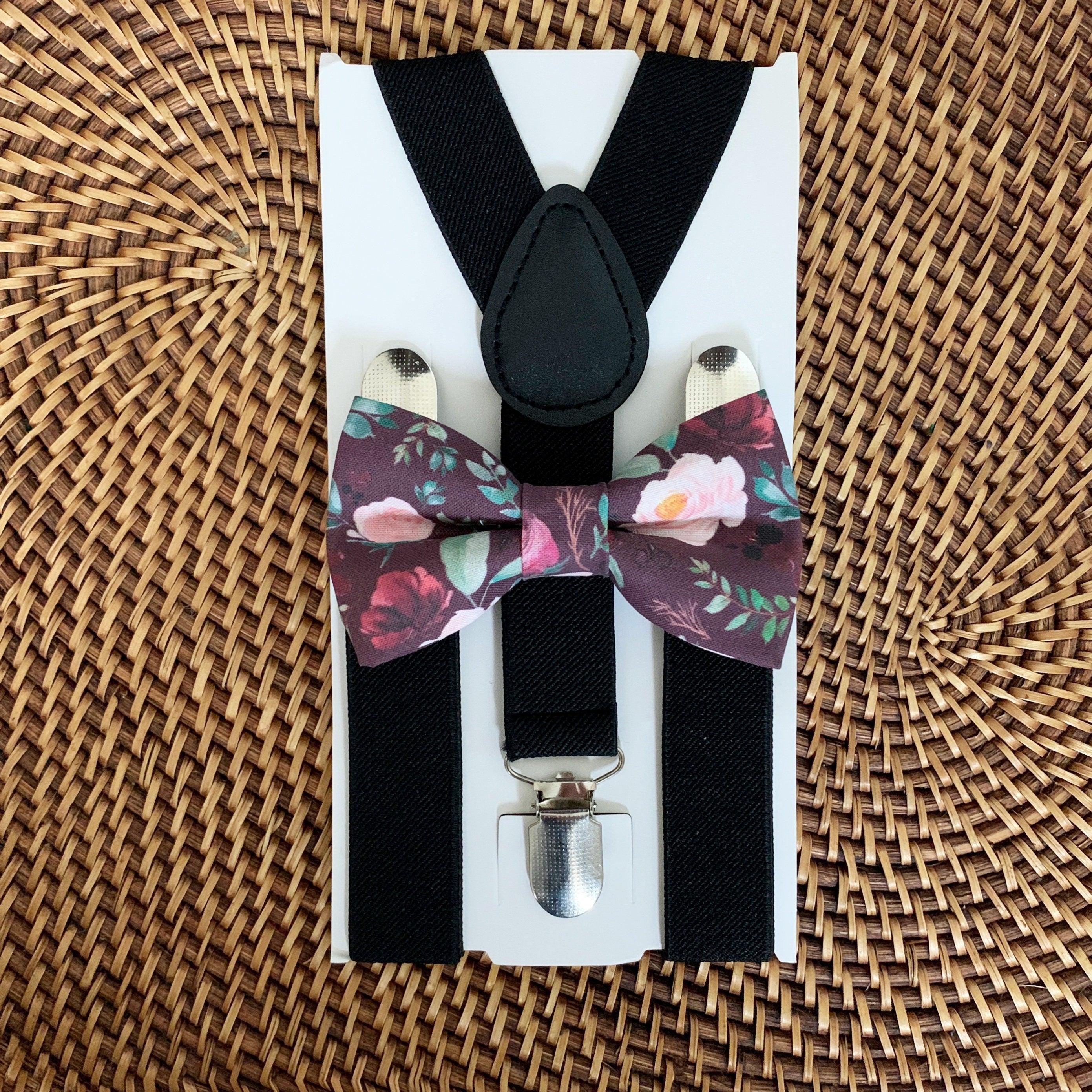 Close up of maroon floral bow tie and black suspenders on a white display card