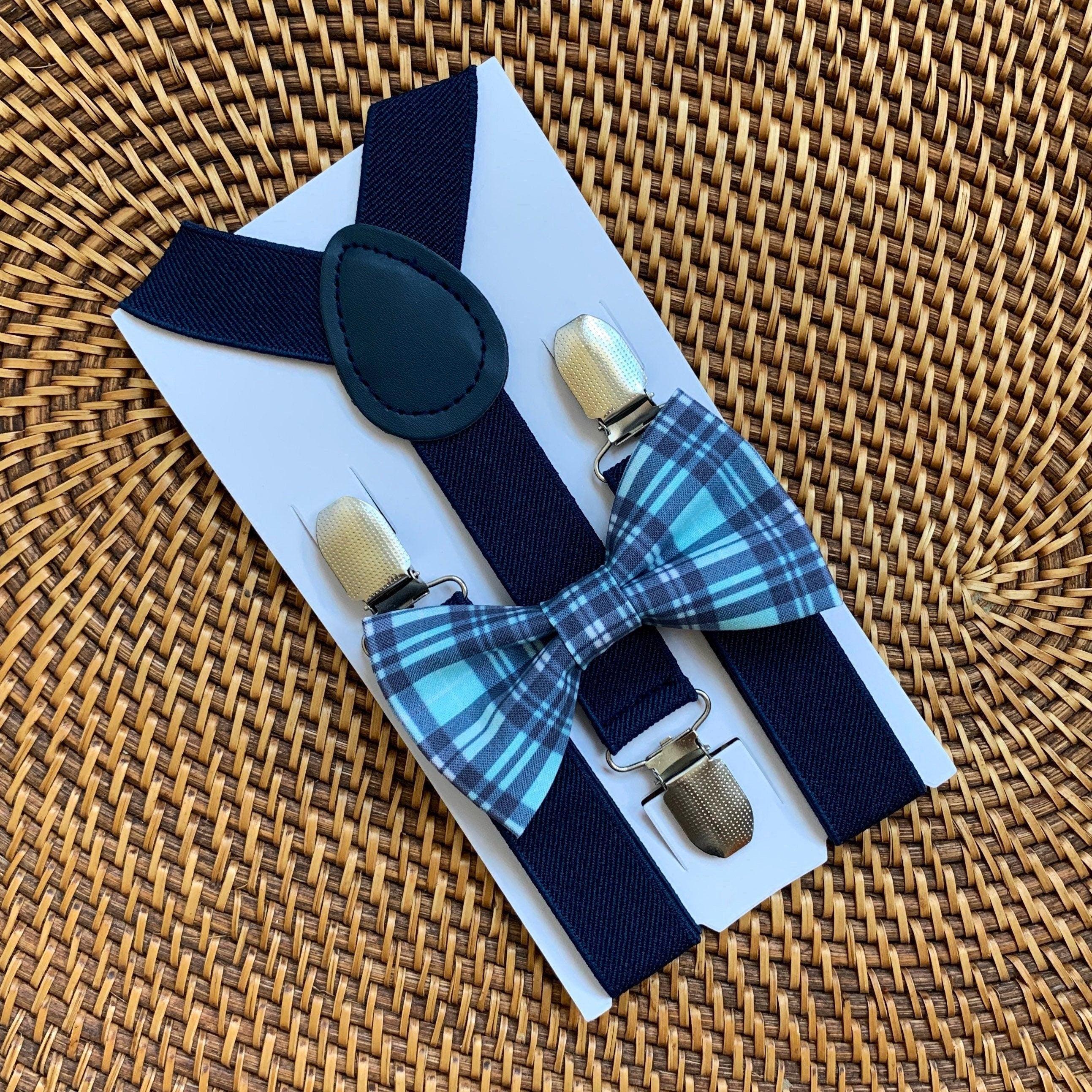 Navy blue suspenders with a plaid bow tie on a woven surface