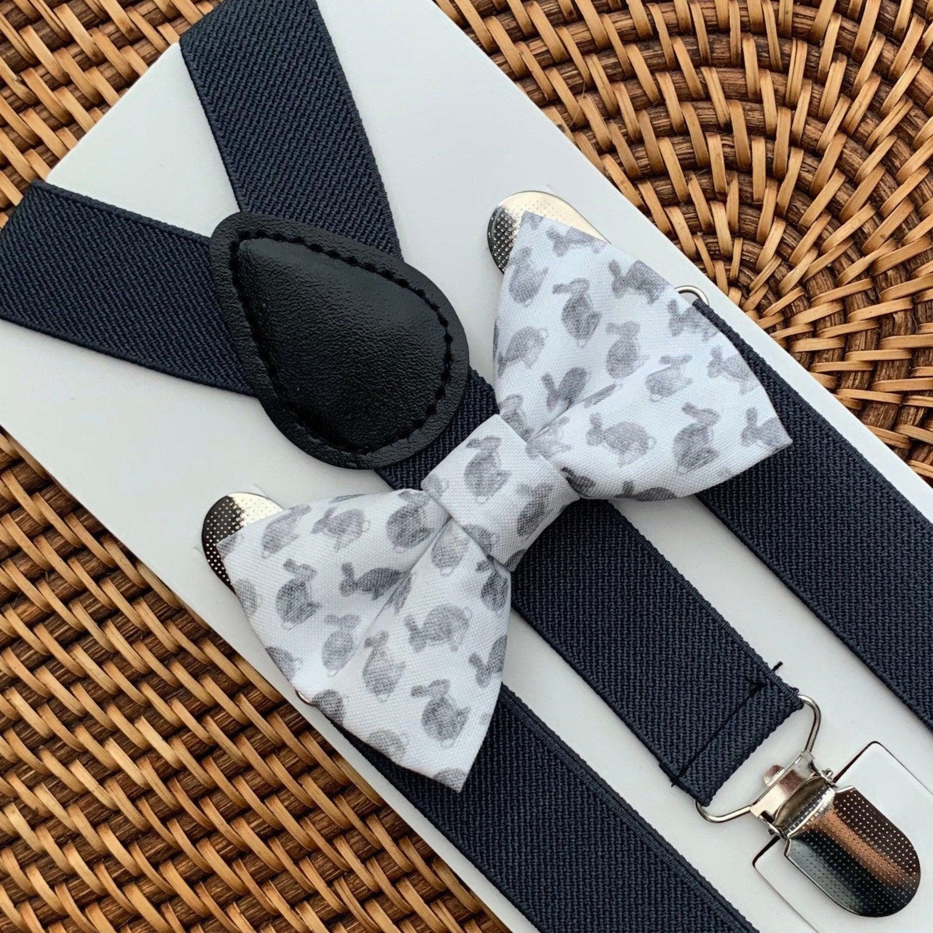 Close up of gray watercolor Easter Bunny bow tie with dark gray suspenders on a white display board against a wicker background