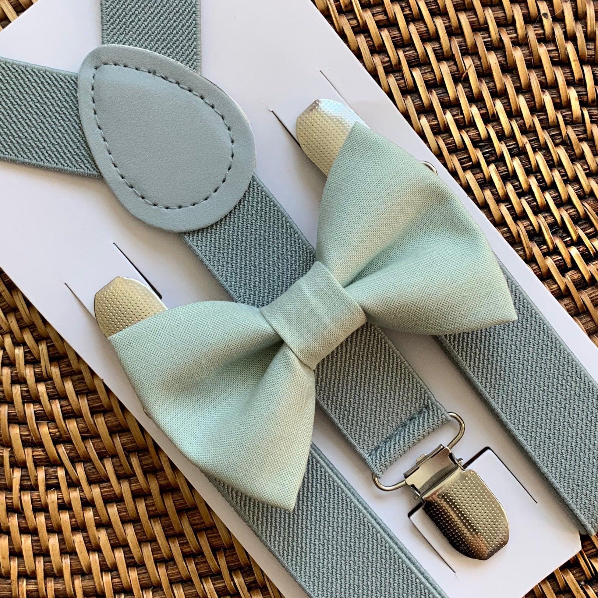 Sage green bow tie and gray suspenders set on a woven surface