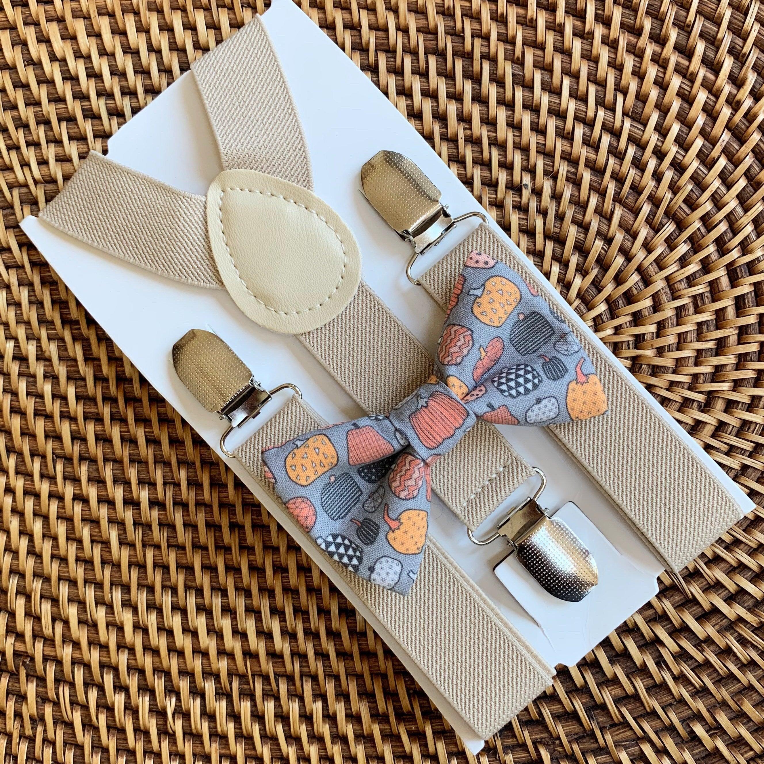 Beige suspenders with a patterned bow tie on a woven surface