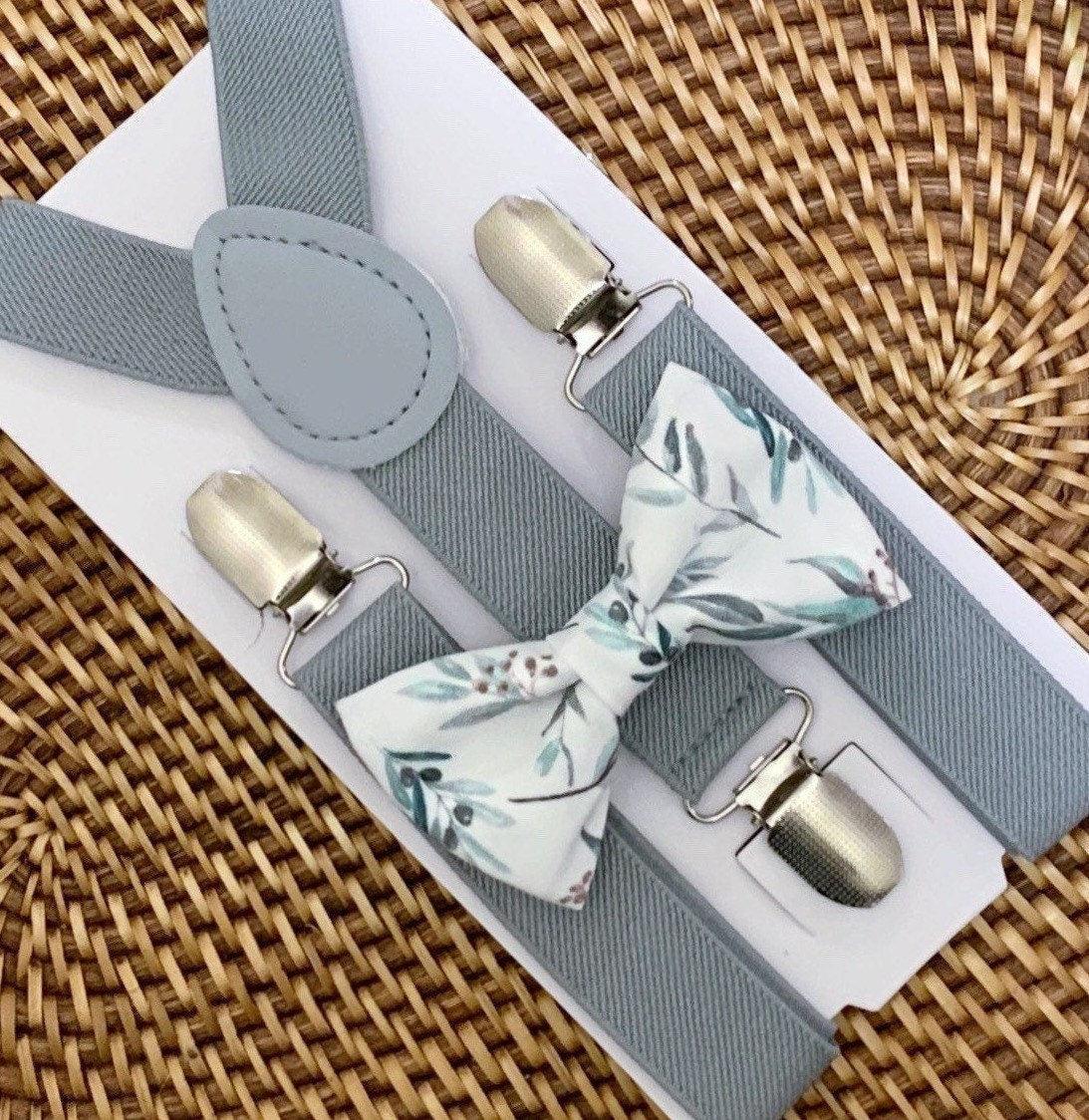 Close-up of sage floral bow tie paired with light gray suspenders on a white display card