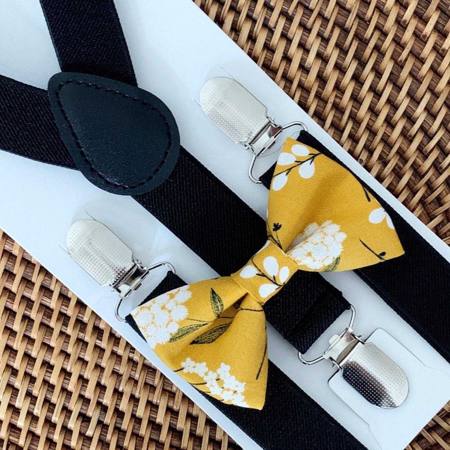 Mustard yellow floral bow tie with black suspenders and metal clips shown on a display card
