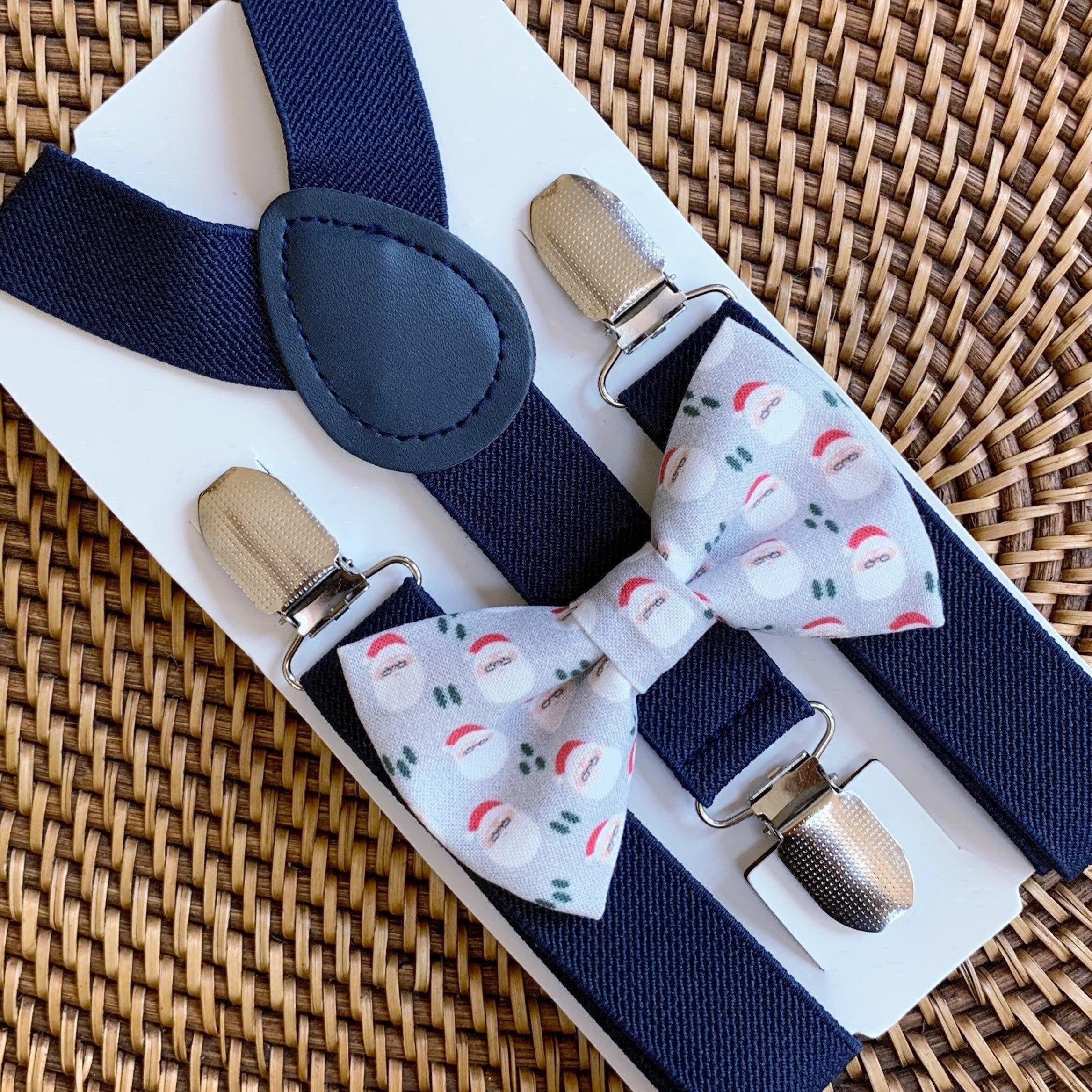 Navy suspenders with beige clip fasteners displayed alongside a Santa themed bow tie.