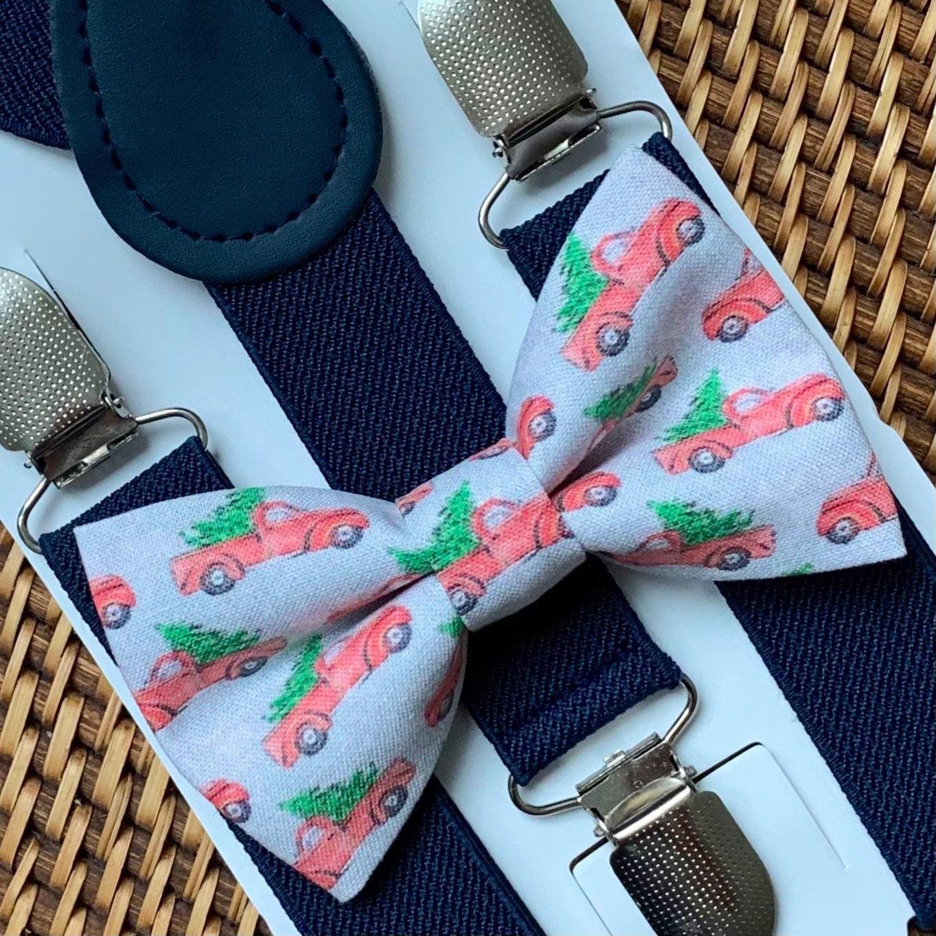Grey Christmas Tree Cars Bow Tie and Navy Suspenders Set laid out with denim suspenders and a light blue bow tie printed with red cars