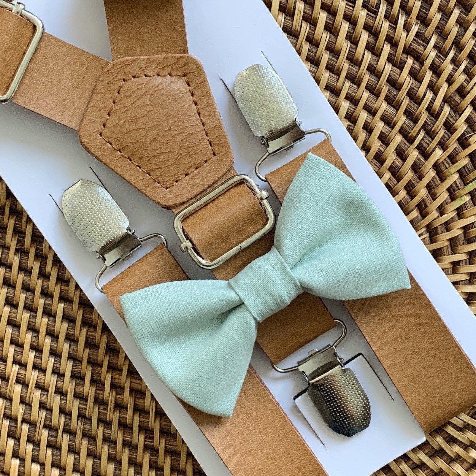 Sage bow tie and tan vegan leather suspenders displayed on packaging card