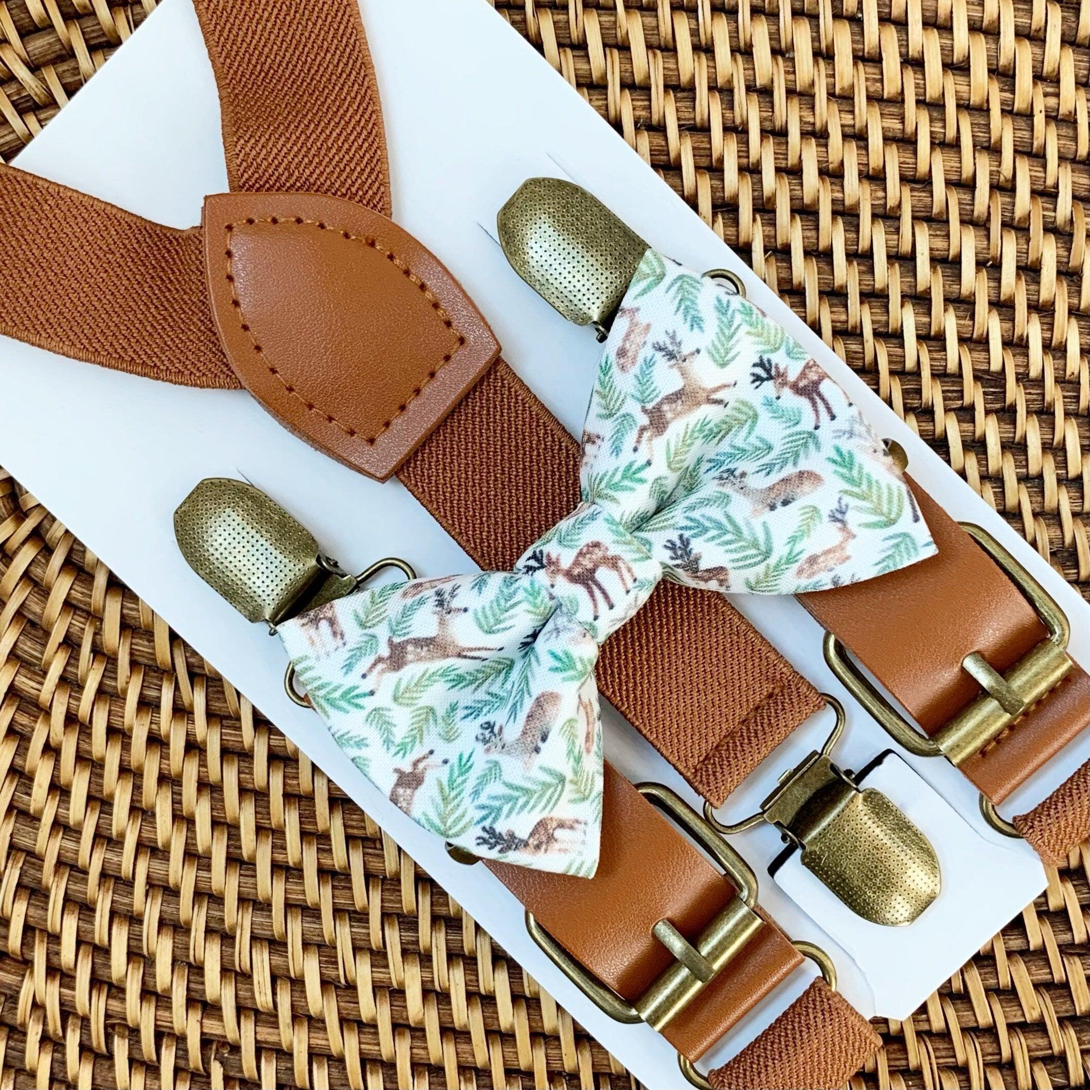 Whimsical reindeer patterned bow tie with cognac buckle suspenders displayed on a white surface