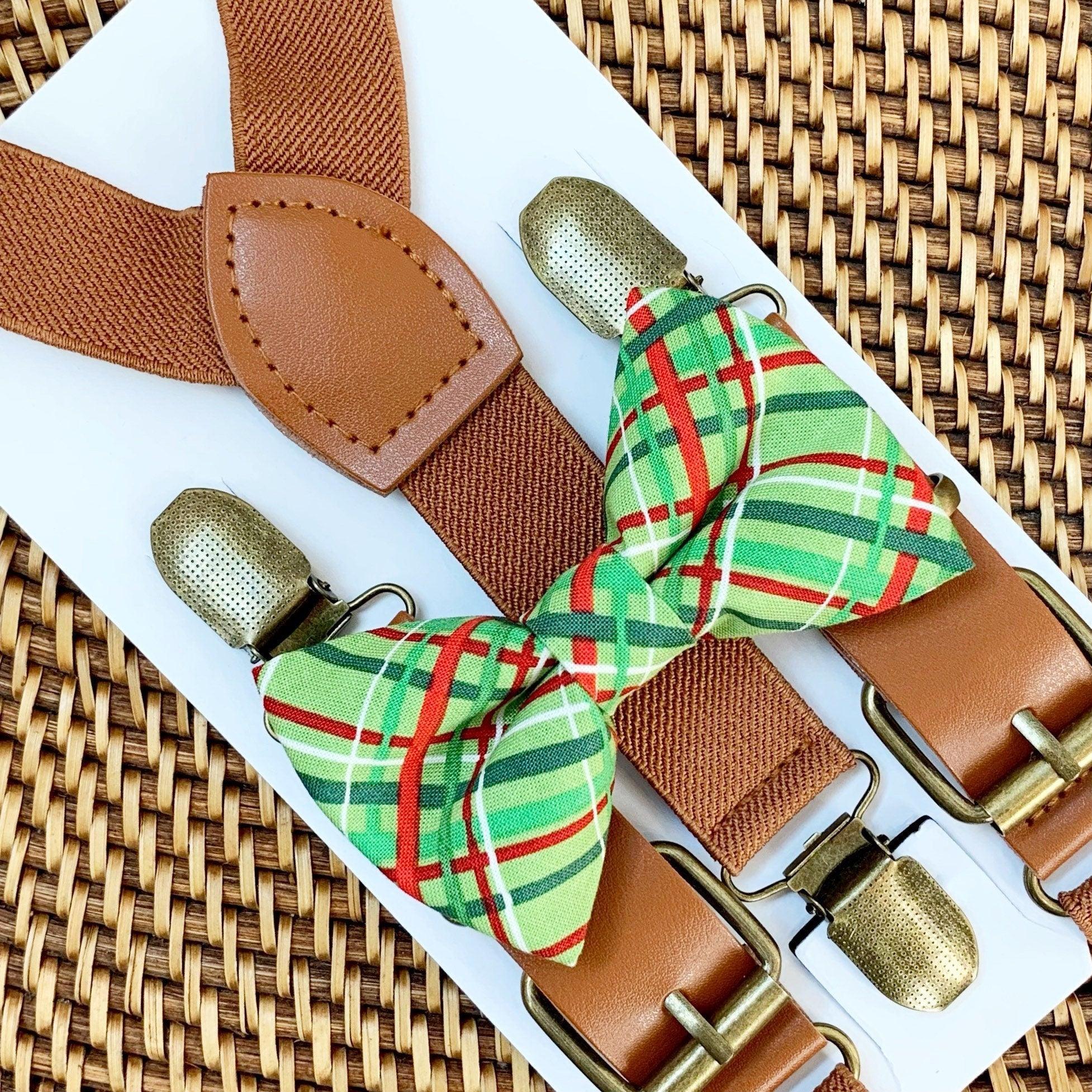 Cognac buckle suspenders with leather patch and a green red plaid bow tie on a white card