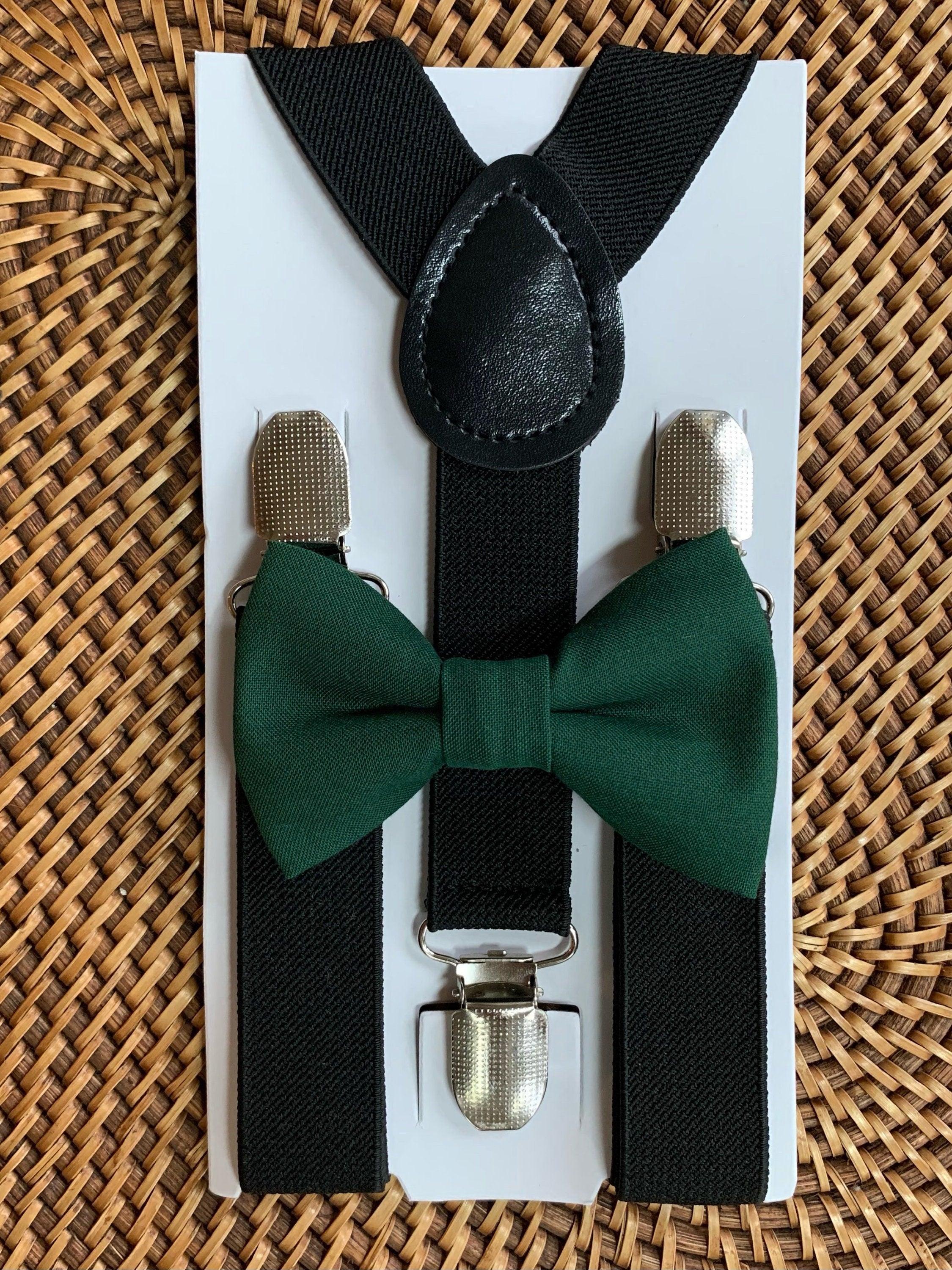 Close up of black suspenders with a green bow tie on a white display card