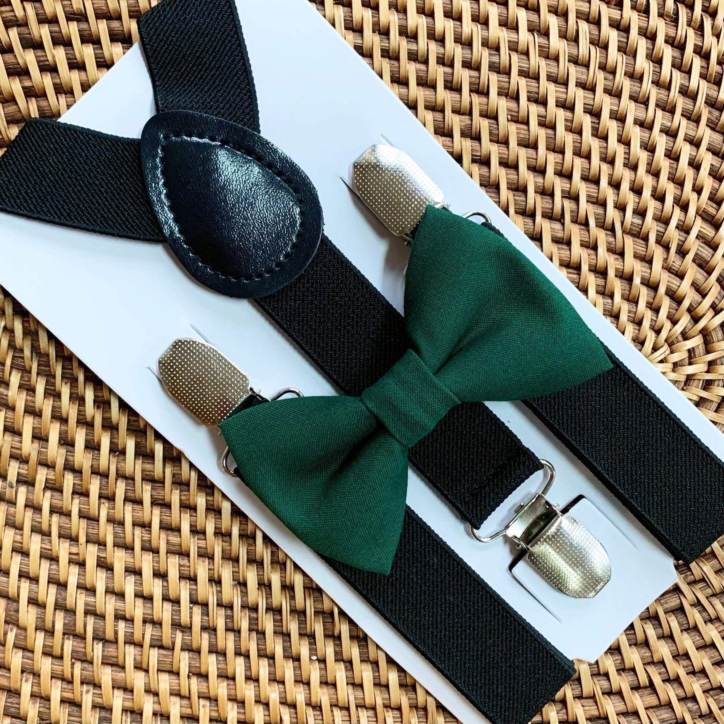 Green bow tie with black suspenders and silver clips displayed on a white card