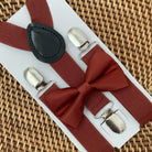 A set of cinnamon red  orange suspenders and a bow tie on a white background, likely made of satin material.
