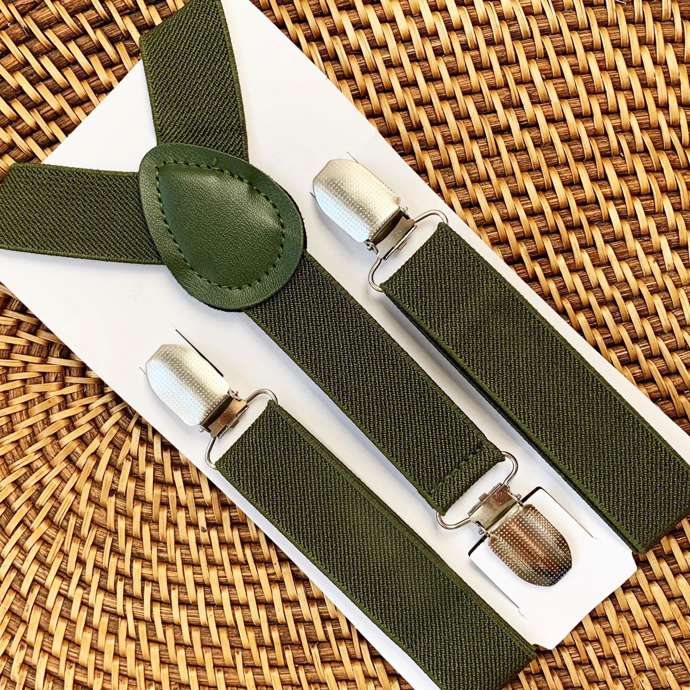 Olive Green suspenders with silver clips on a woven surface