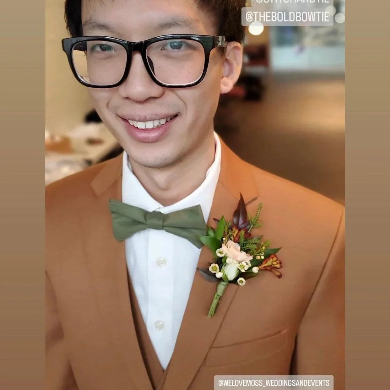 Close up of a man in a tan suit wearing an olive bow tie and floral boutonniere