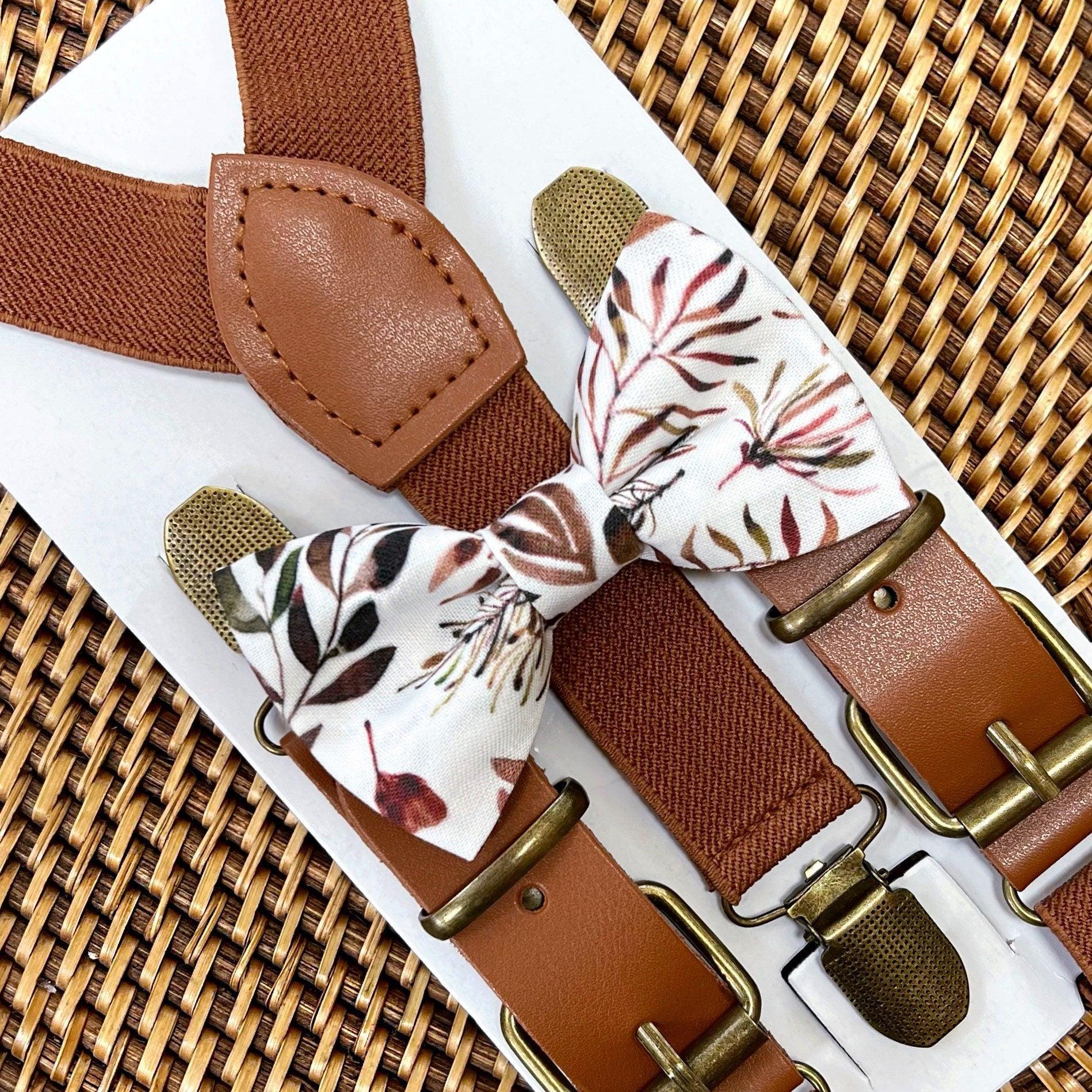 A set of terracotta floral bow tie and cognac buckle suspenders displayed on a card, with the bow tie showing a floral pattern and the suspenders in solid color with buckles.