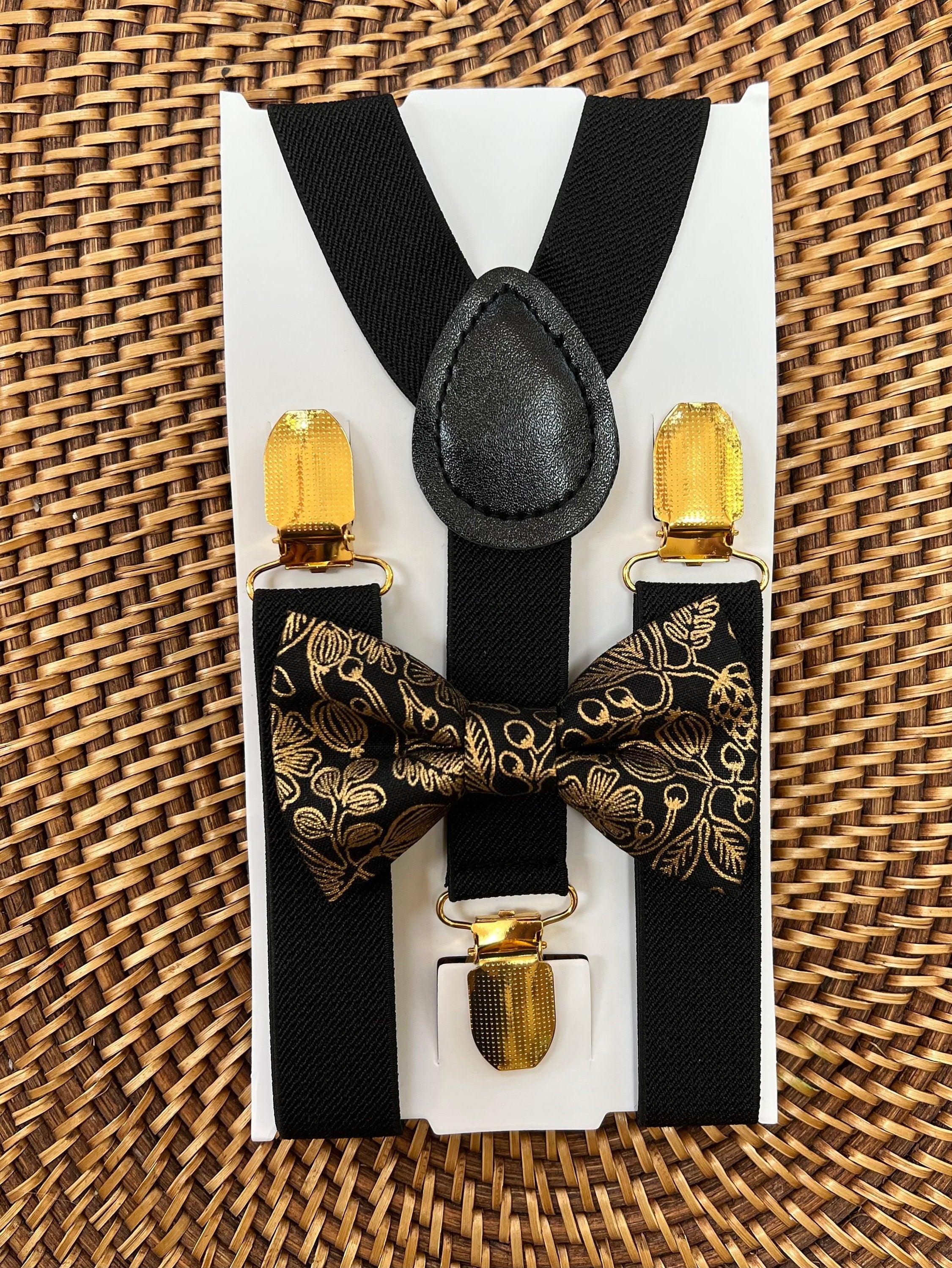 Black and gold bow tie and suspenders set shown on a white card with gold clip ends and a leather knot centerpiece