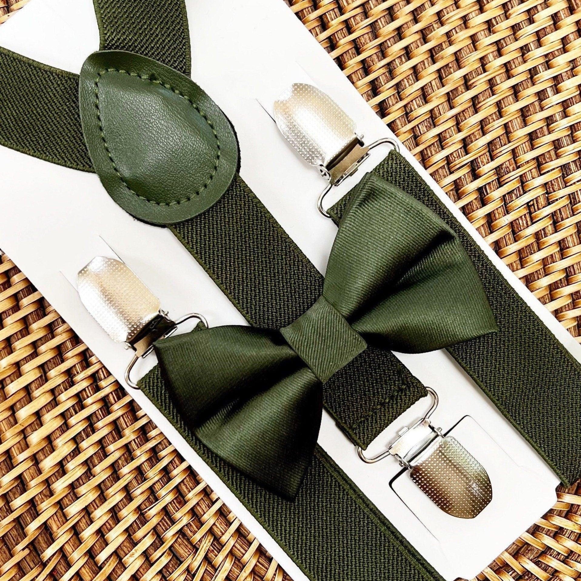 Olive green satin bow tie with matching suspenders laid on a white presentation card against a woven backdrop.