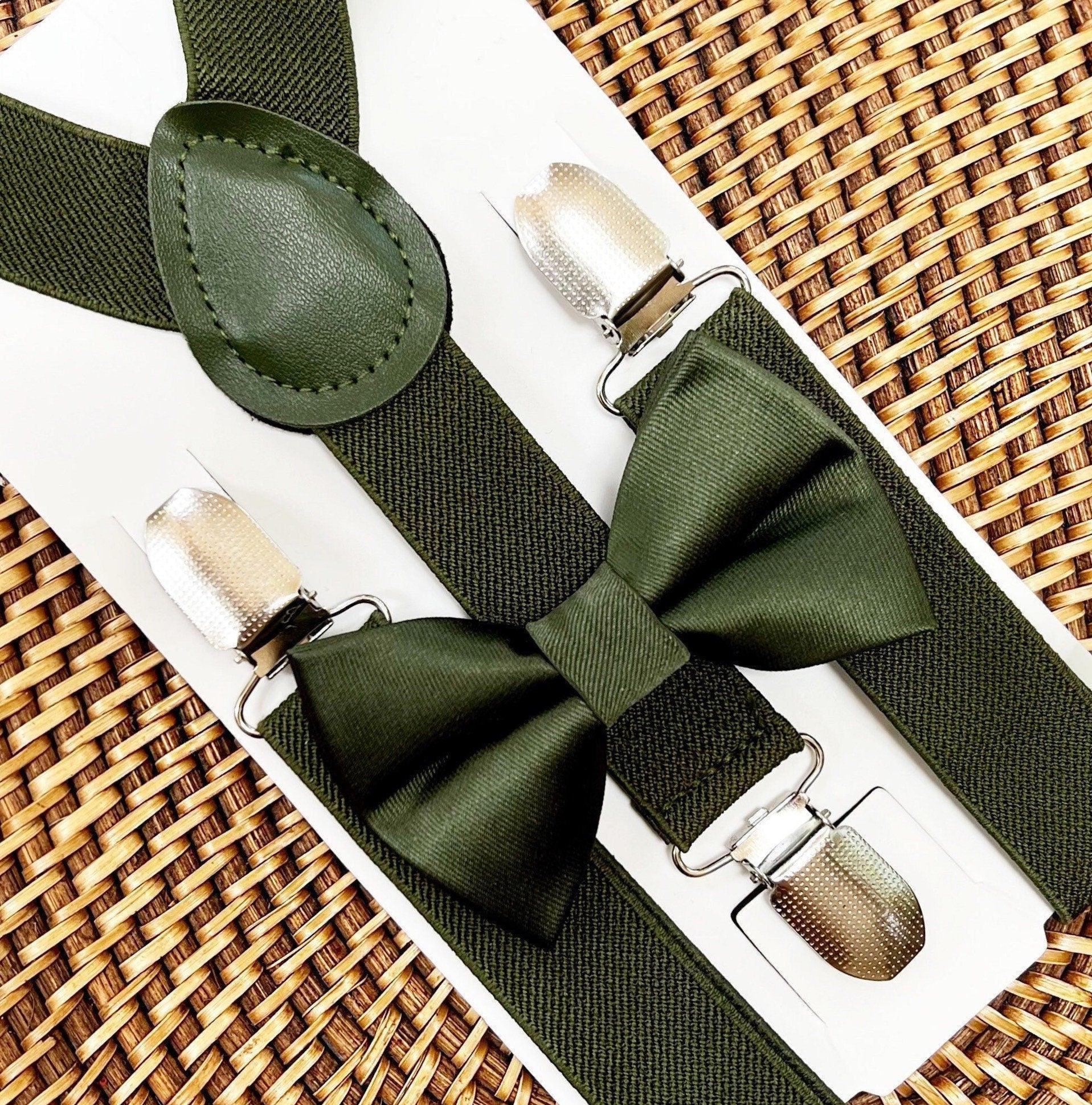 Olive green satin bow tie with matching suspenders laid on a white presentation card against a woven backdrop.