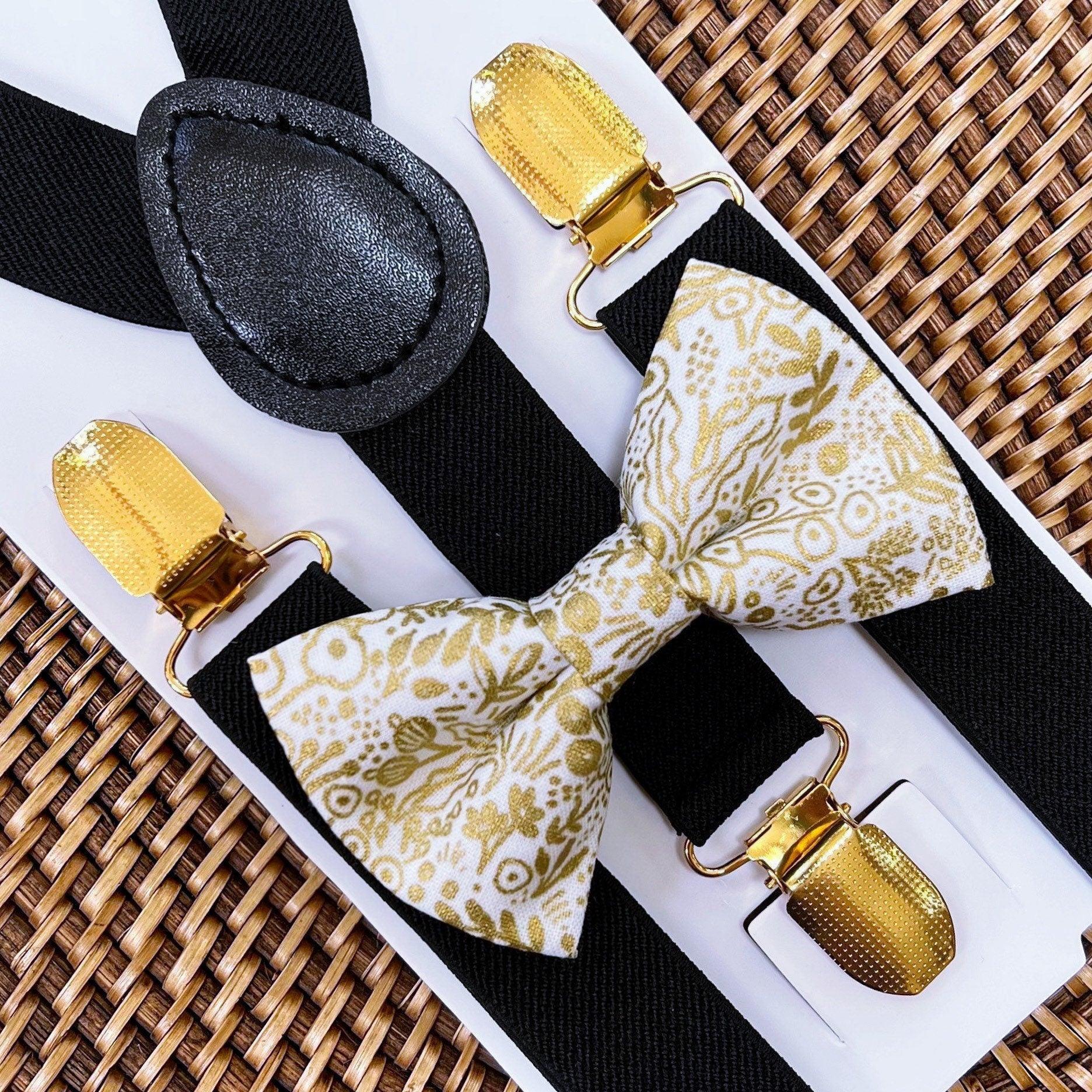Gold bow tie and suspenders- Close up of gold floral bow tie with gold suspenders clips on a white background.