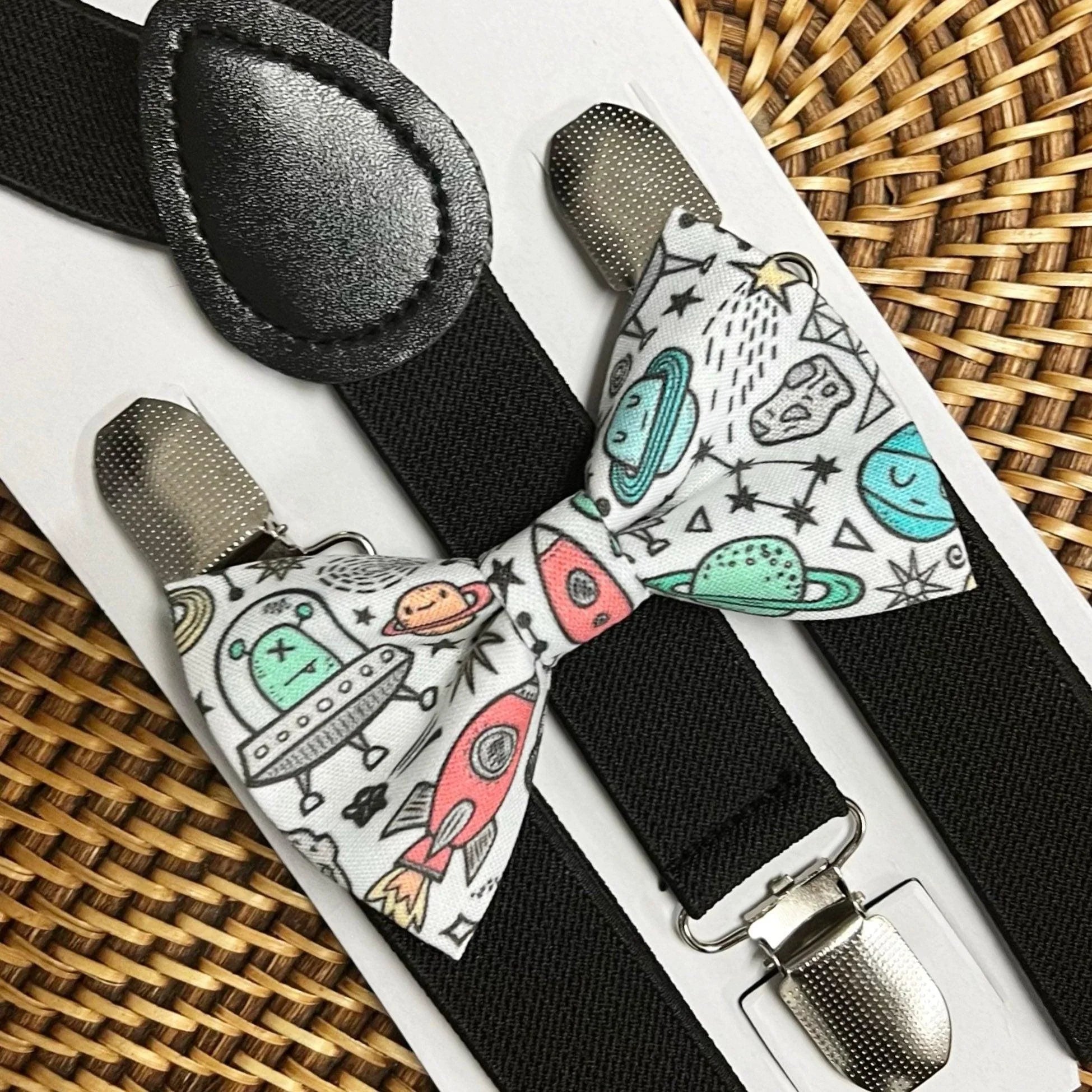 Outer Space Bow Tie and Black Suspenders set shown on a white display board with space themed print and metal clips
