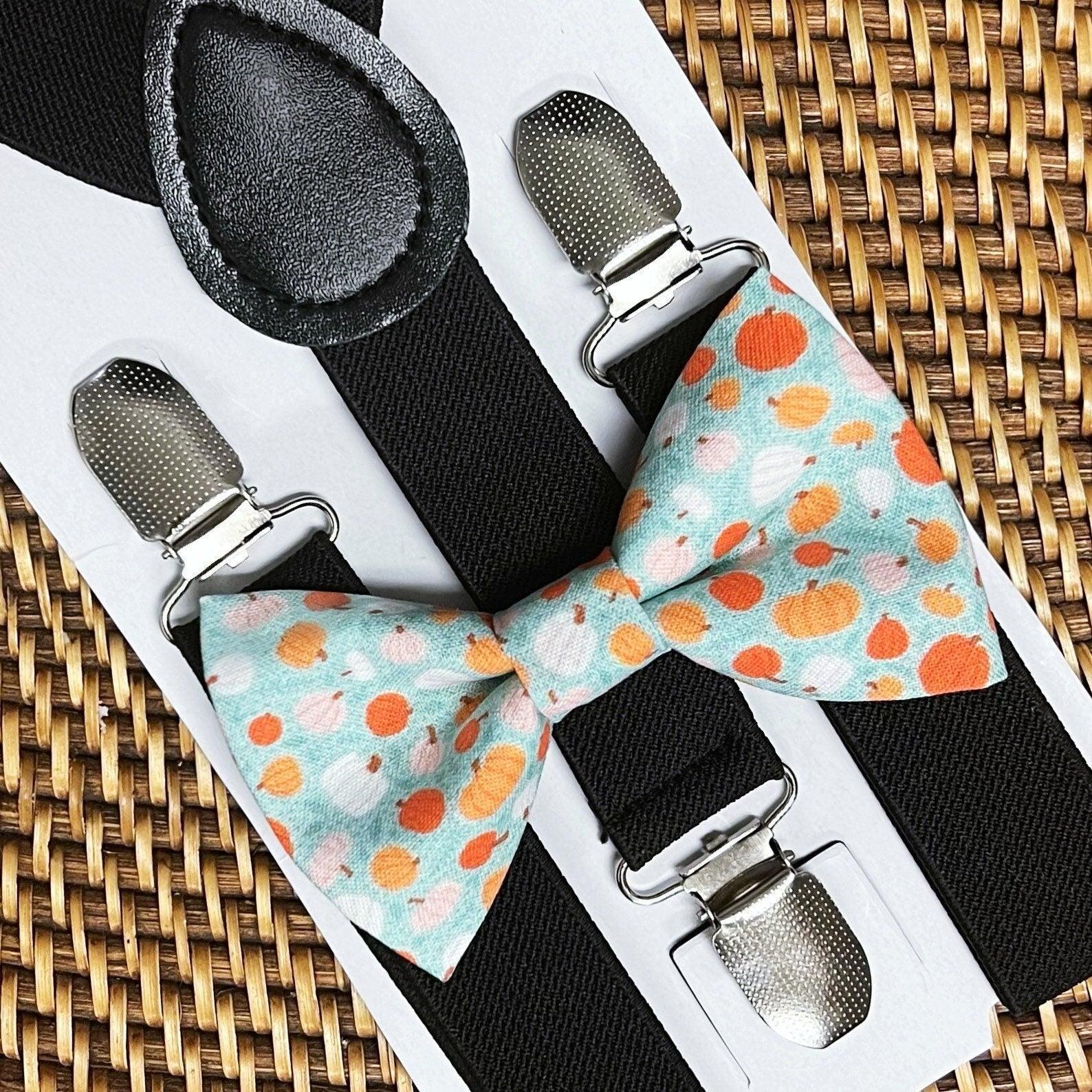 Pumpkin themed teal bow ties with silver clip suspenders on a white display card