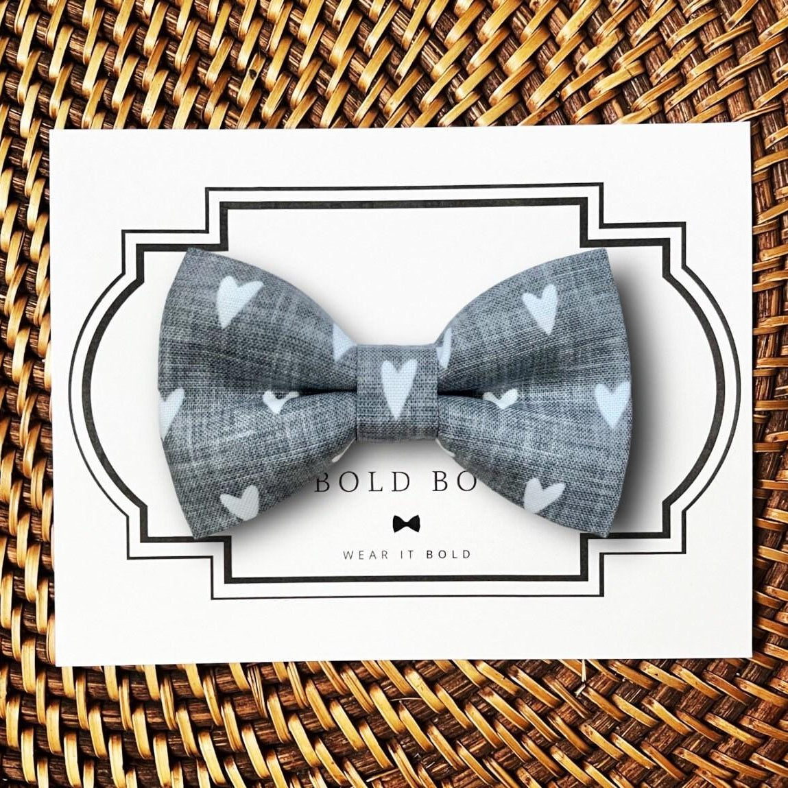 Product graphic showcasing the back of a pre-tied bow tie in a red and black buffalo plaid pattern, resting on a rustic wood surface. Two black elastic loops are attached to the center knot to slide onto a pet collar. Overlay text reads: Back of Bow Tie (may not be actual bow tie in listing).