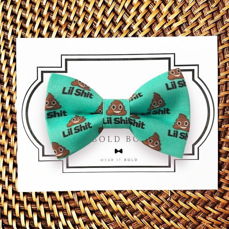 Turquoise bow tie with poop emoji pattern and Lil Shit text on a white display card
