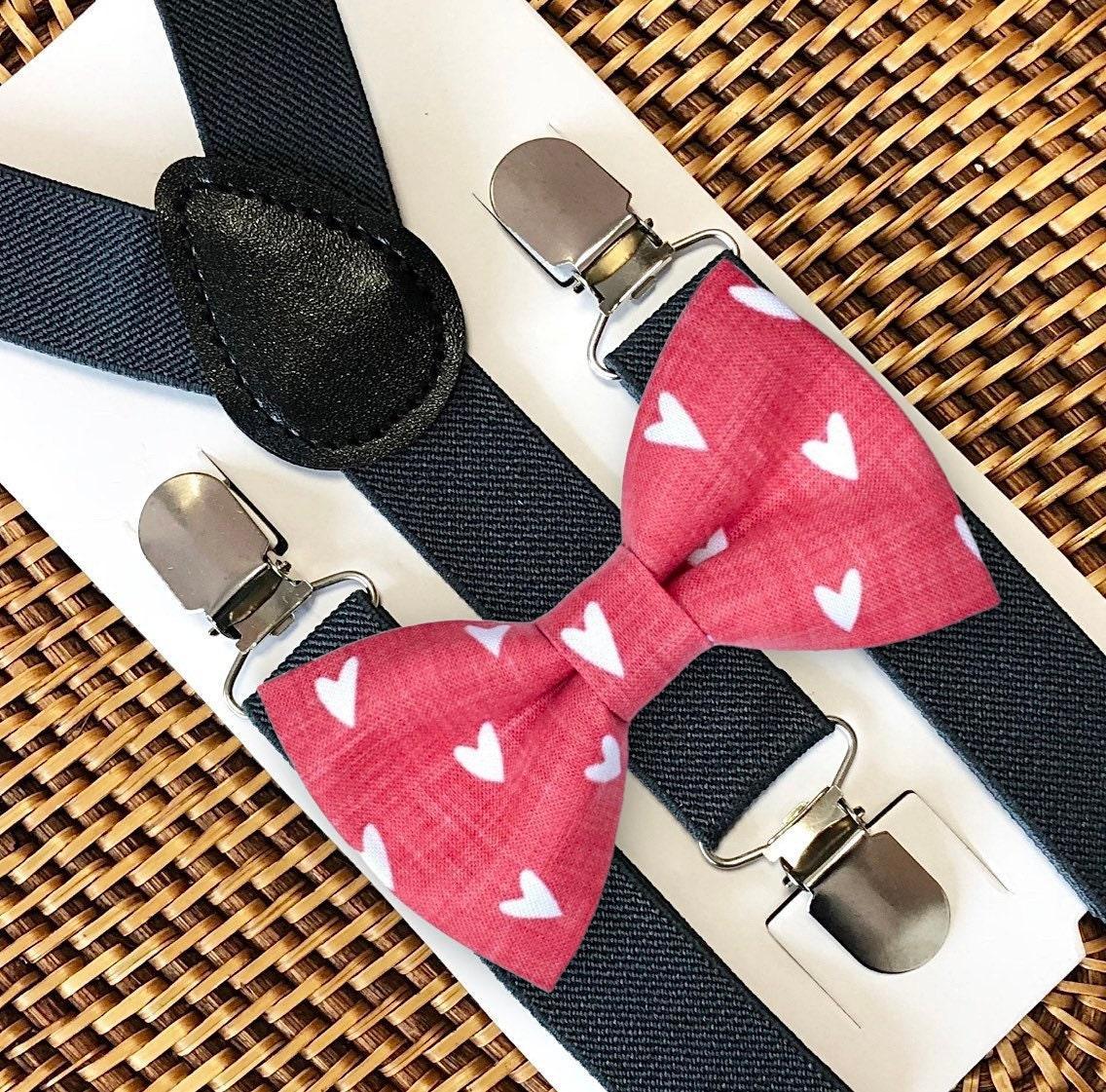 Red hearts bow tie with dark grey suspenders set on a textured surface
