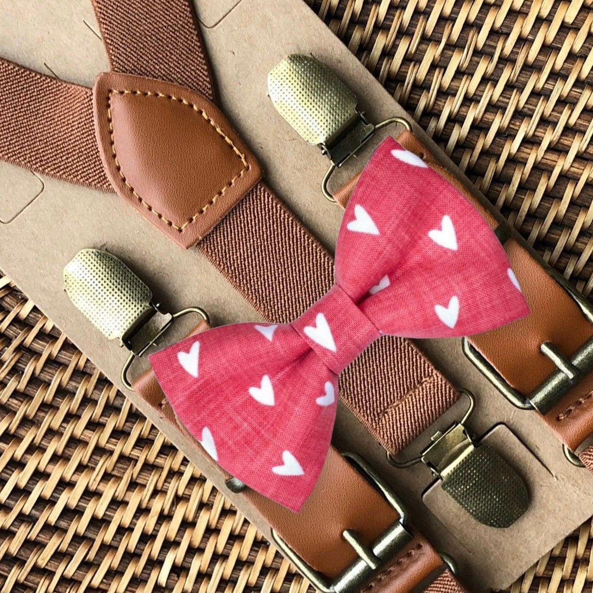 Pink bow tie with white heart pattern paired with cognac buckle suspenders on brown straps