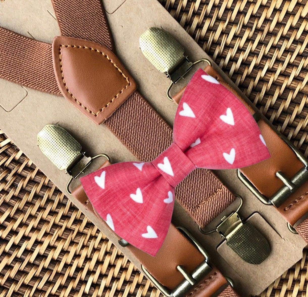 Pink bow tie with white heart pattern paired with cognac buckle suspenders on brown straps