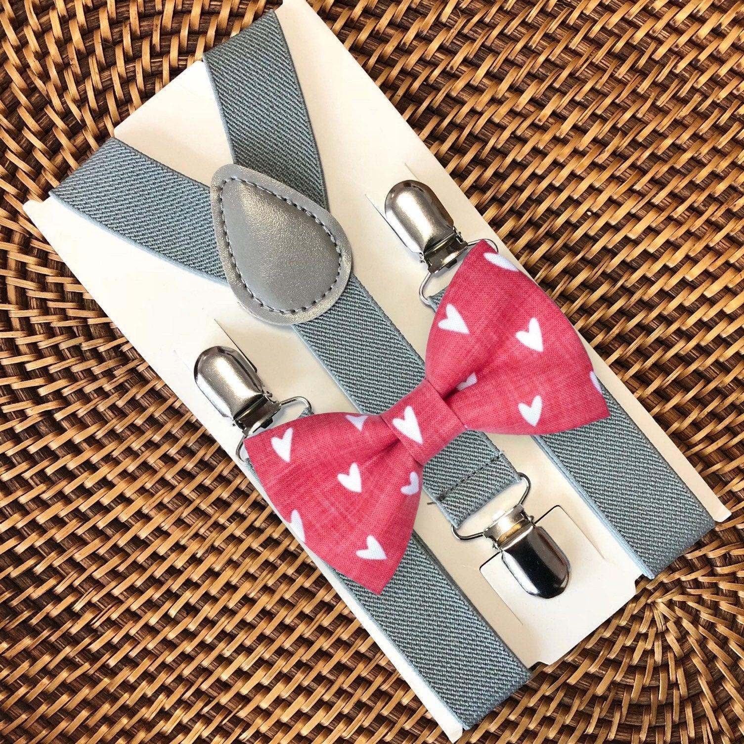 Red Hearts Bow Tie with light gray suspenders arranged on packaging over a woven surface