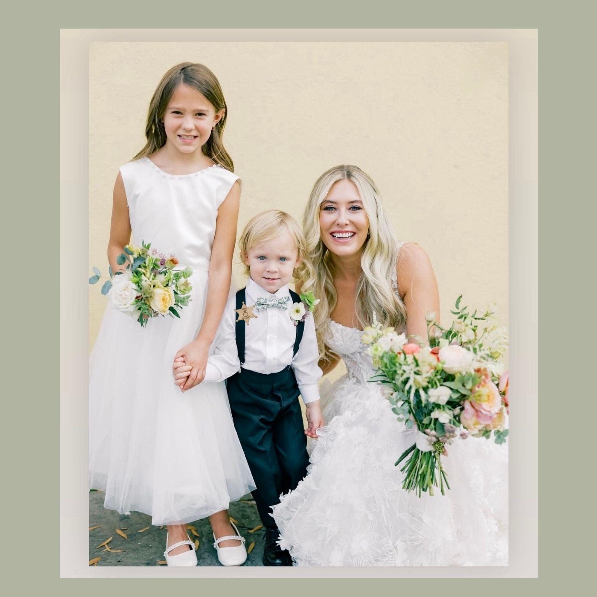 Bride and flower girl with a young ring bearer wearing a ring security badge and dinosaur bow tie
