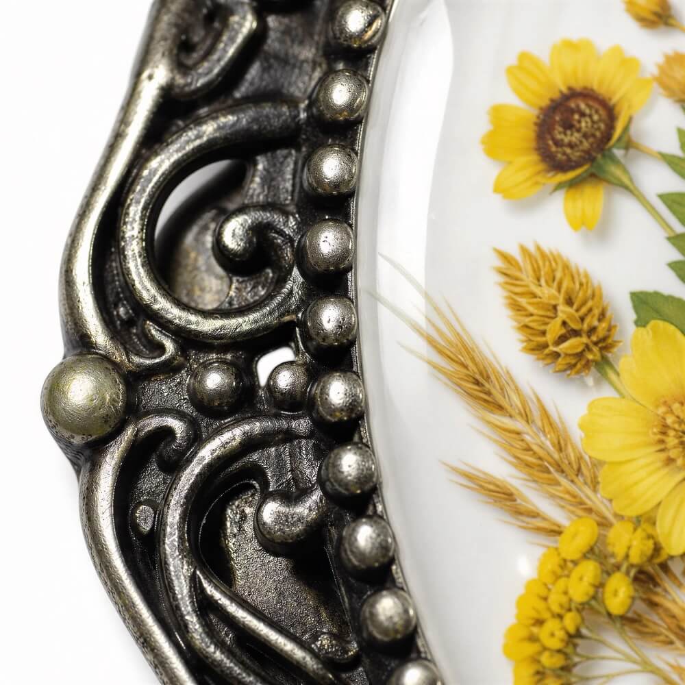a close-up view of a decorative metal frame with a floral design on it, and a close-up view of yellow flowers on a white background.