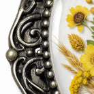 a close-up view of a decorative metal frame with a floral design on it, and a close-up view of yellow flowers on a white background.
