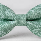 A close-up view of a green bow tie with a floral pattern.