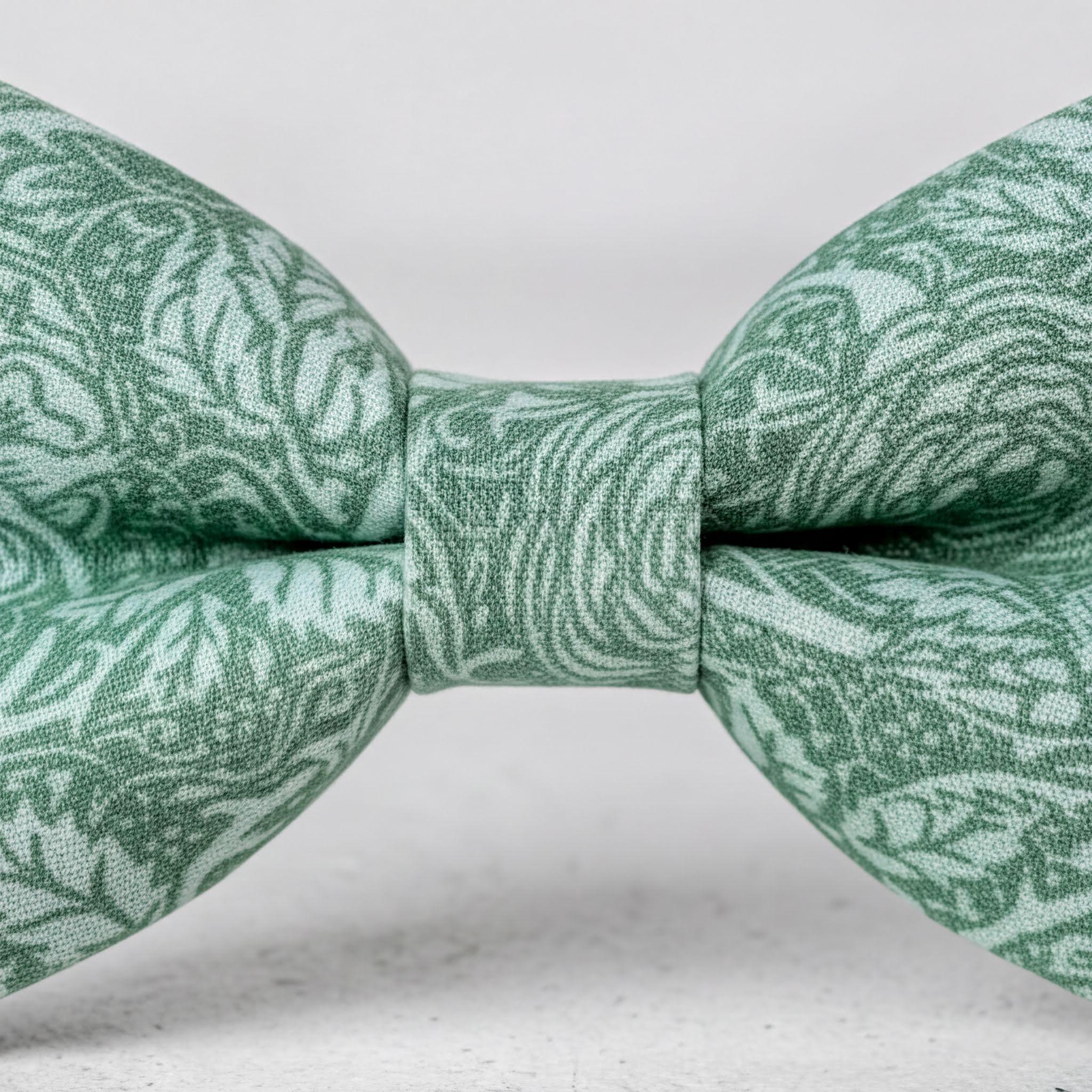 A close-up view of a green bow tie with a floral pattern.